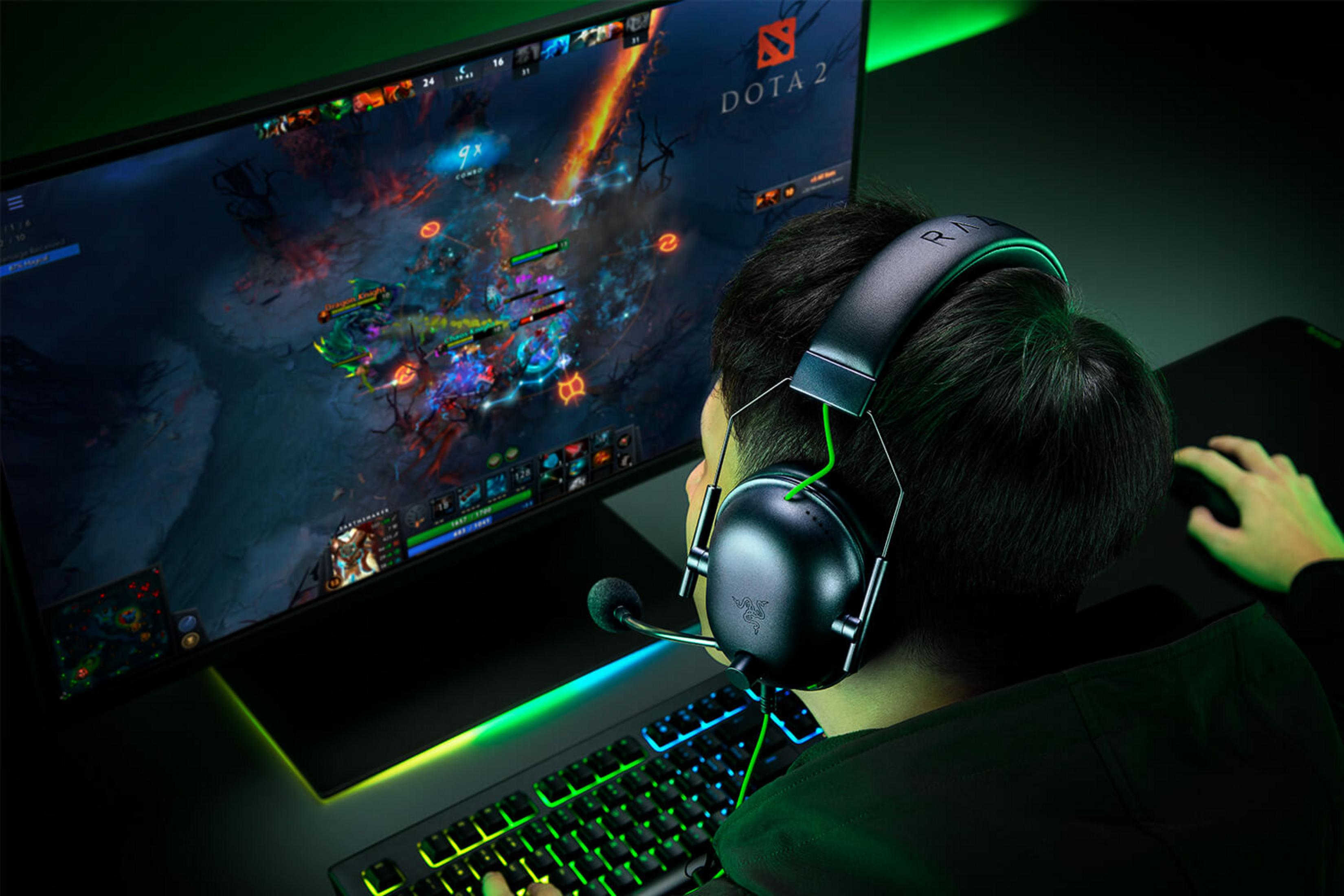 Ein Spieler mit Kopfhörern spielt Dota 2 auf einem beleuchteten Keyboard.