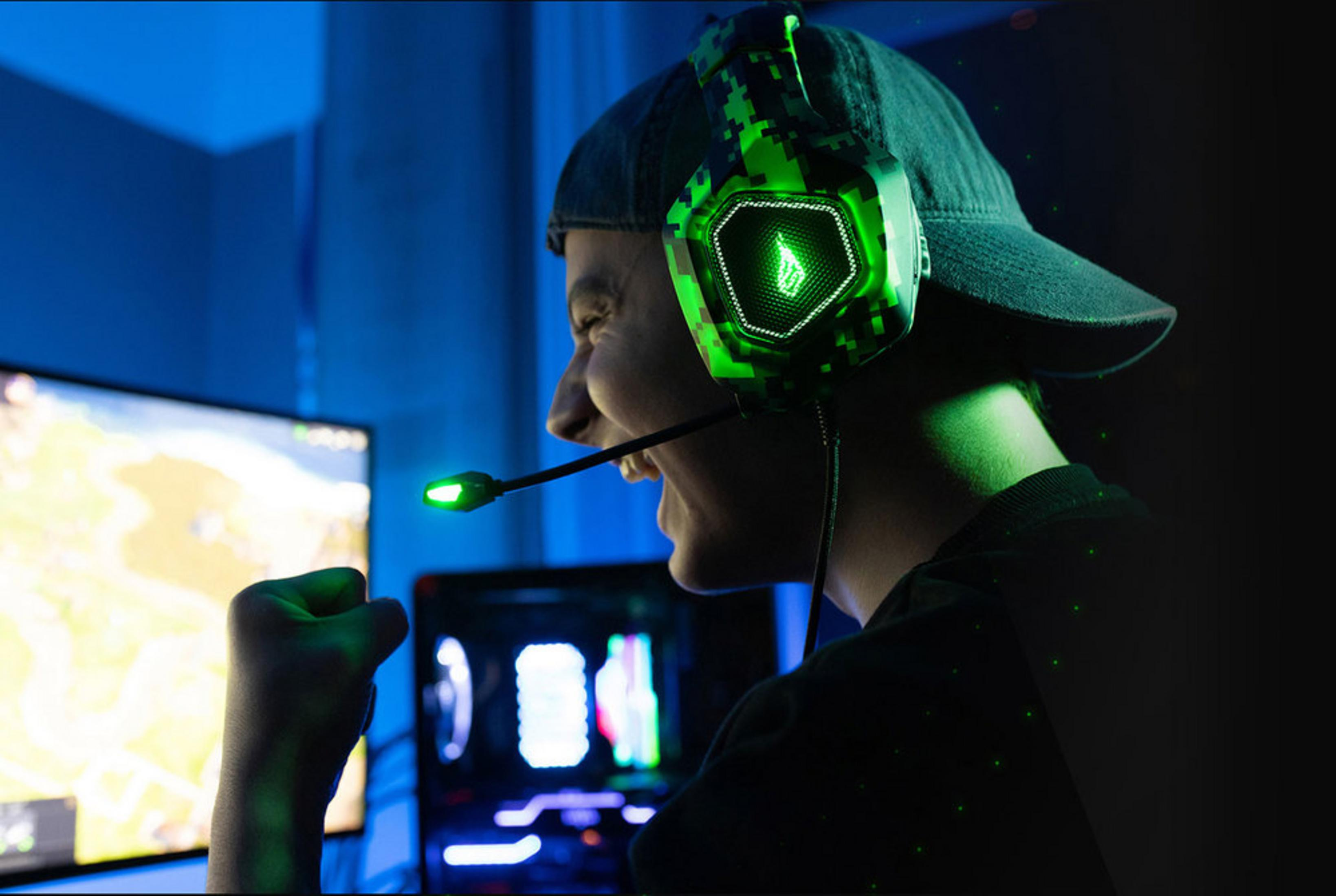 A gamer in green headphones cheers in front of a glowing screen.