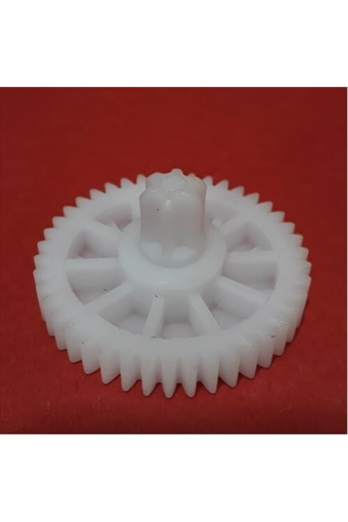 Kırmızı arka plan üzerinde çok sayıda dişe sahip beyaz plastik dişli.
