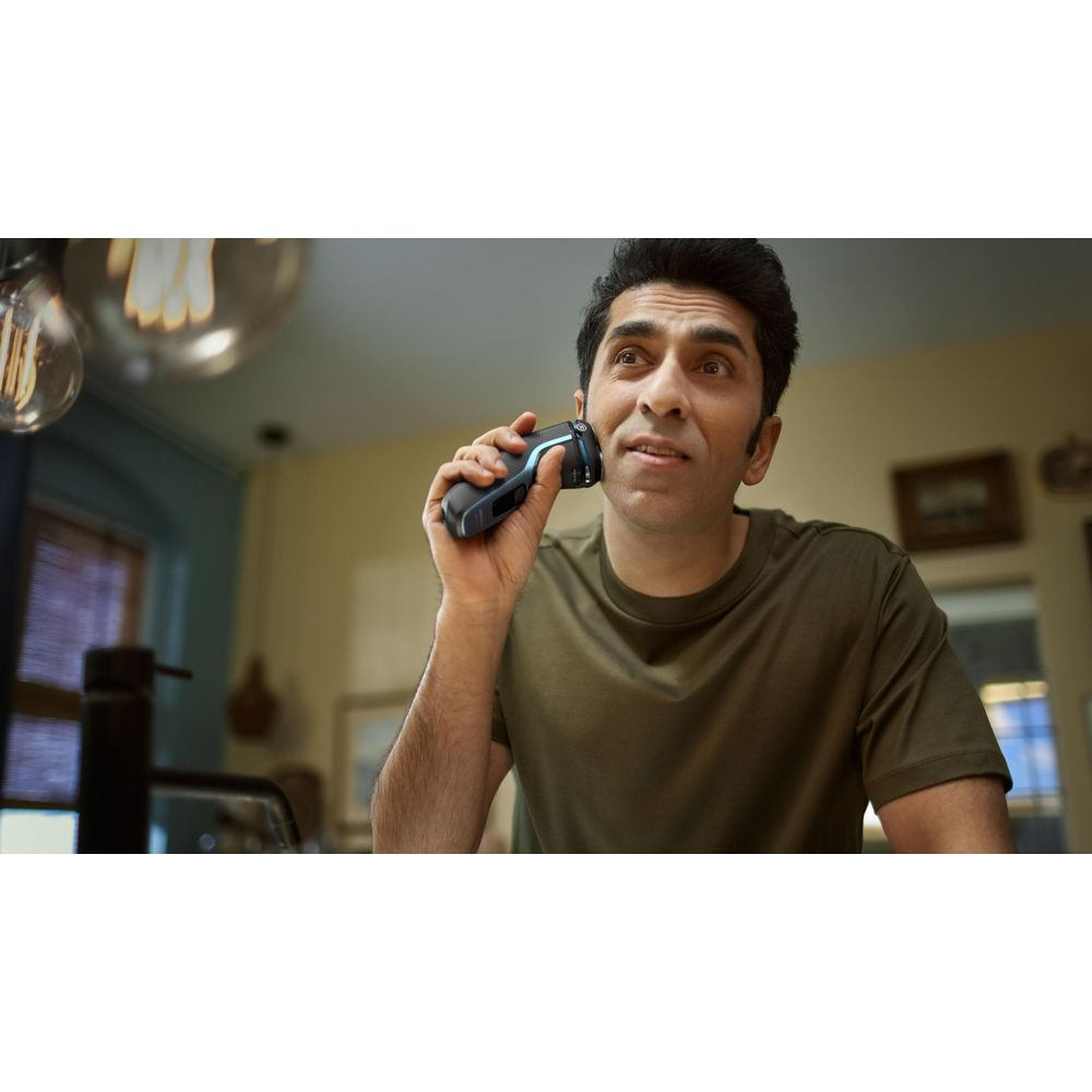 Mężczyzna goli twarz golarką elektryczną.