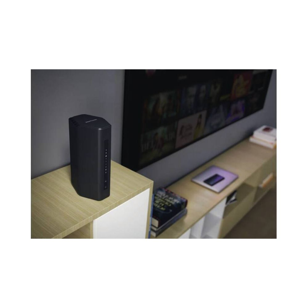 Czarny router stoi na drewnianej półce przed telewizorem.