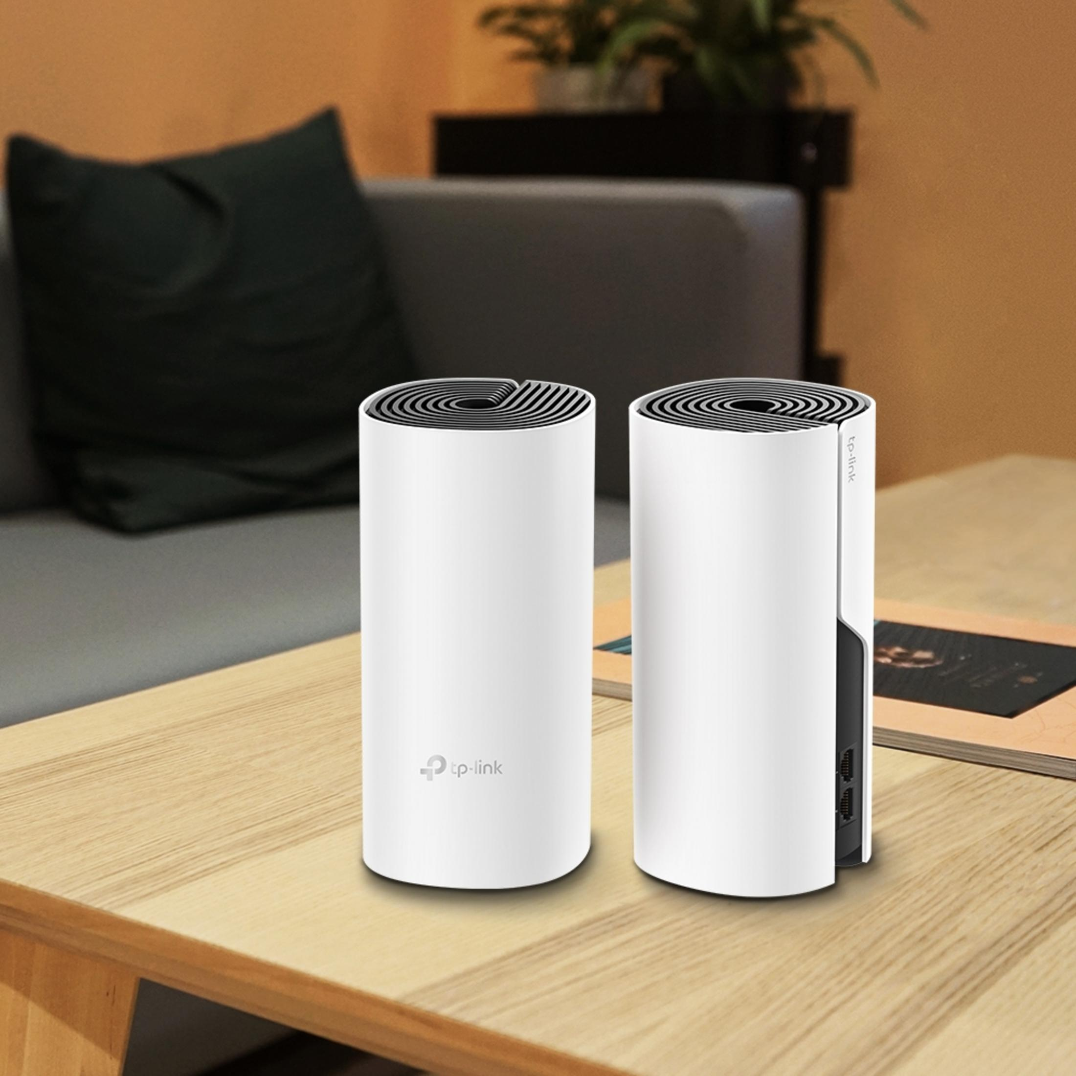Zwei weiße TP-Link-Router stehen auf einem Holztisch. Im Hintergrund ein Sofa.