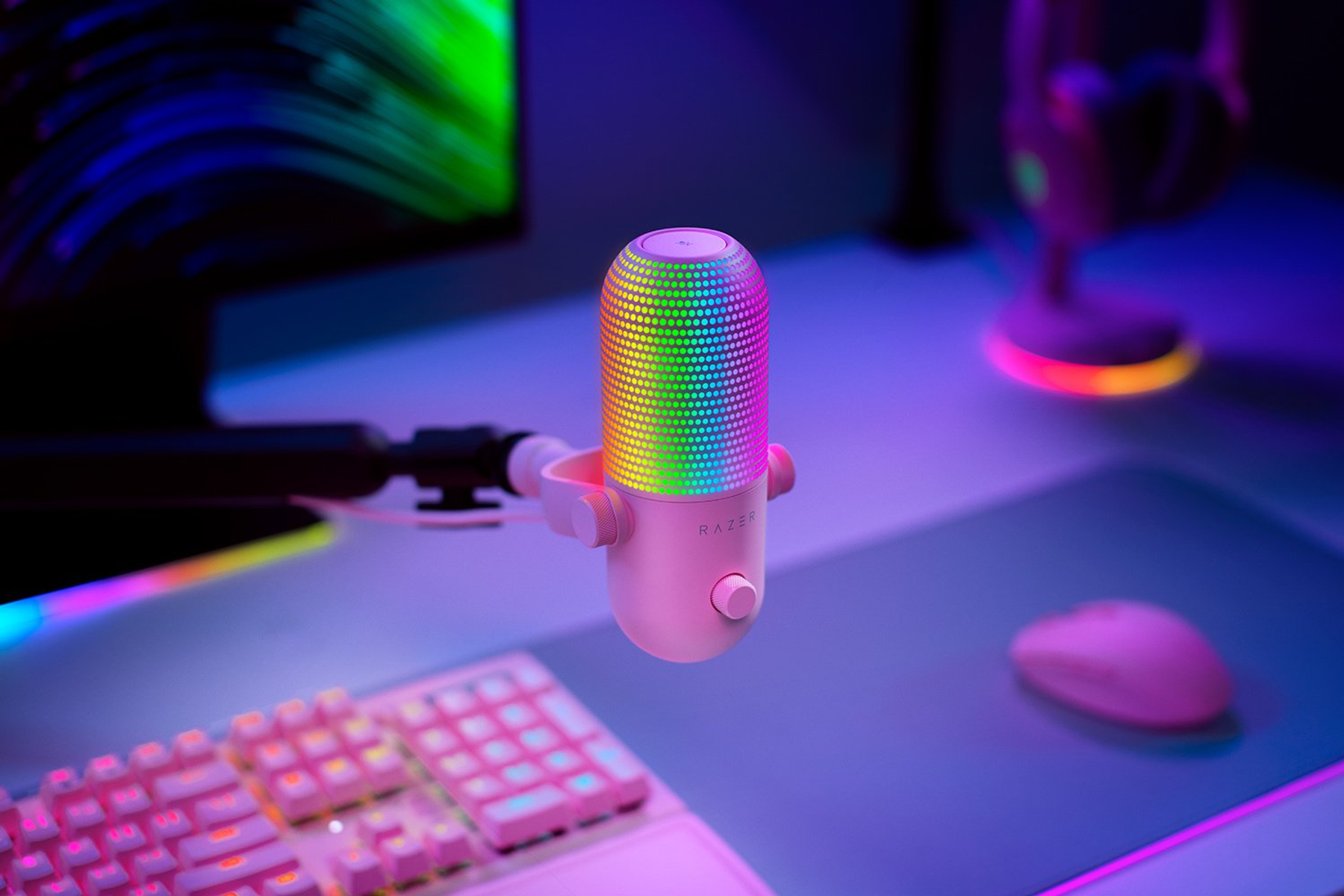 Ein pinkes Mikrofon mit RGB-Licht leuchtet neben einer Tastatur und Maus.