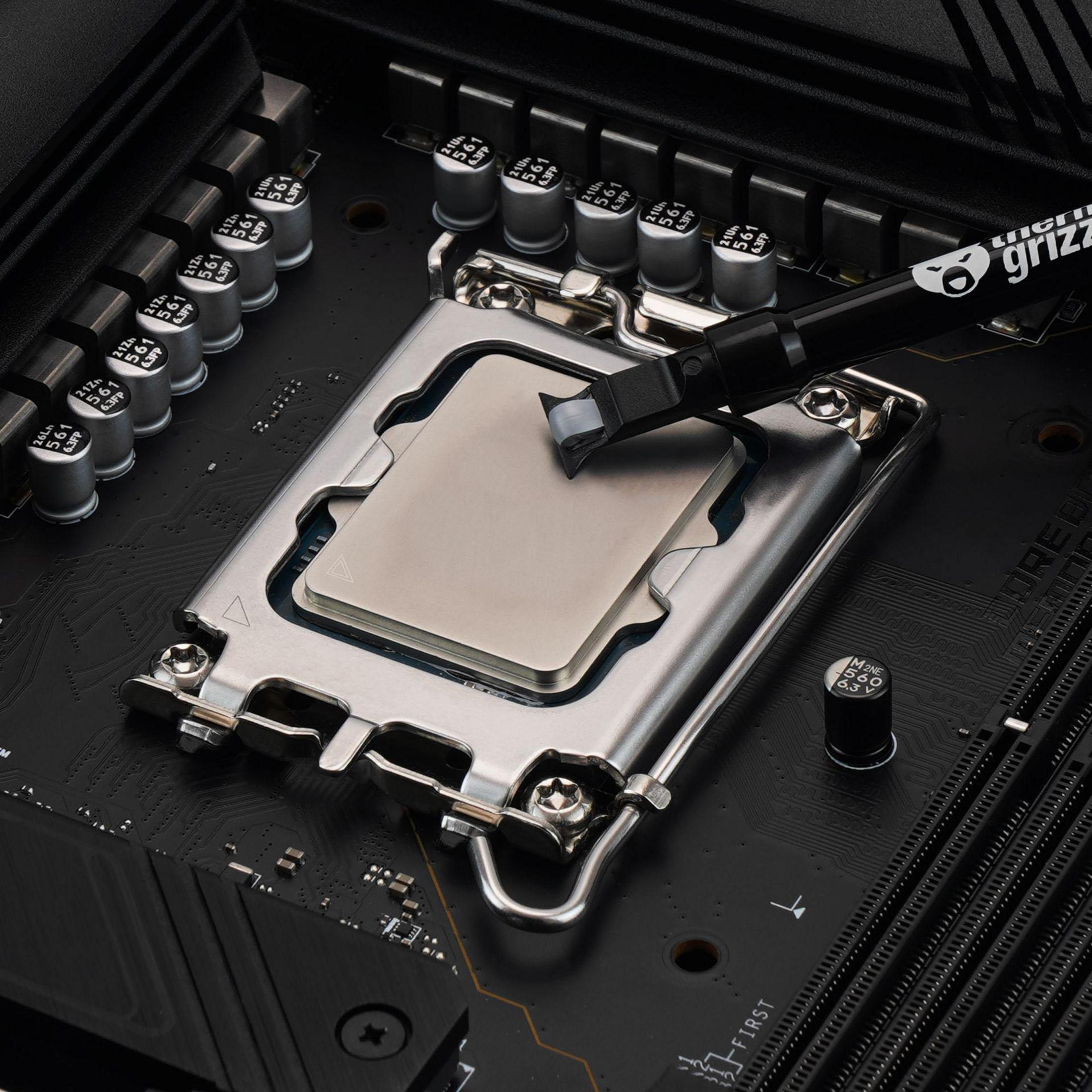 Ein Prozessor wird auf einem Motherboard montiert, mit Wärmeleitpaste aufgetragen.