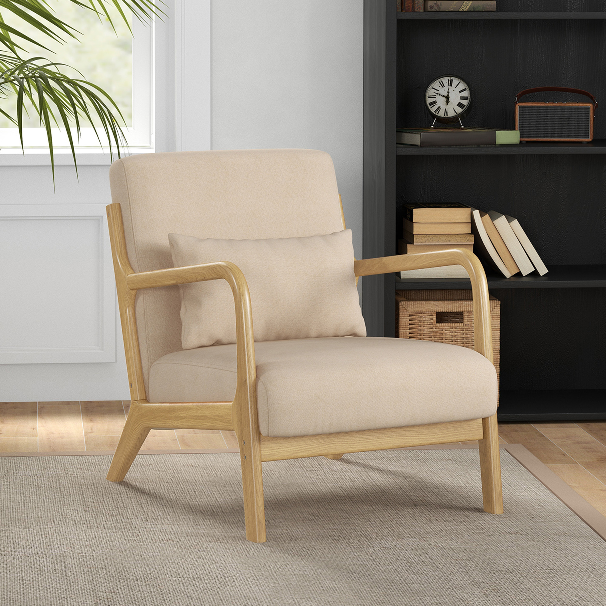 Un sillón beige con marco de madera está sobre una alfombra, frente a una estantería negra.