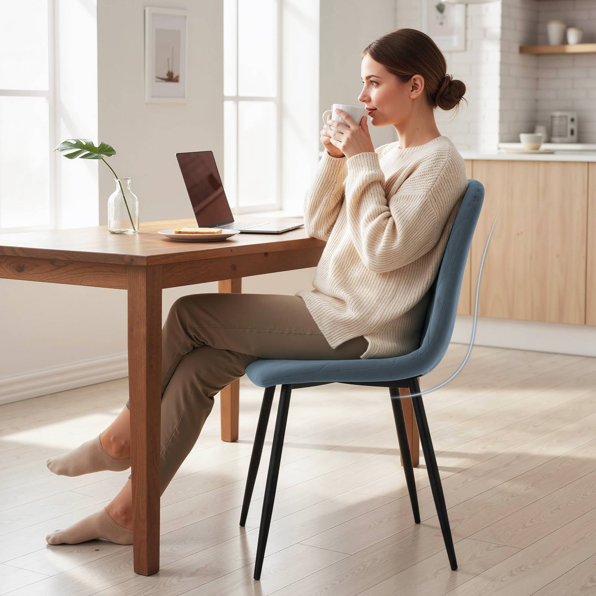 Una mujer bebe café en una mesa de madera con portátil y tostada.