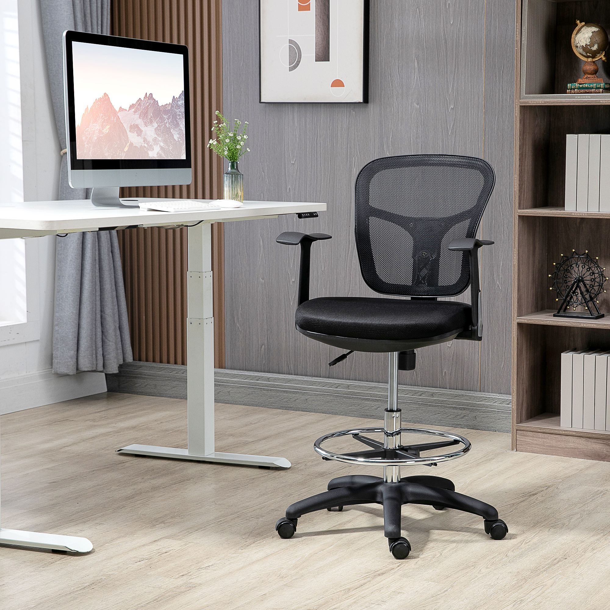 Una silla de oficina negra con respaldo de malla junto a un escritorio con monitor.