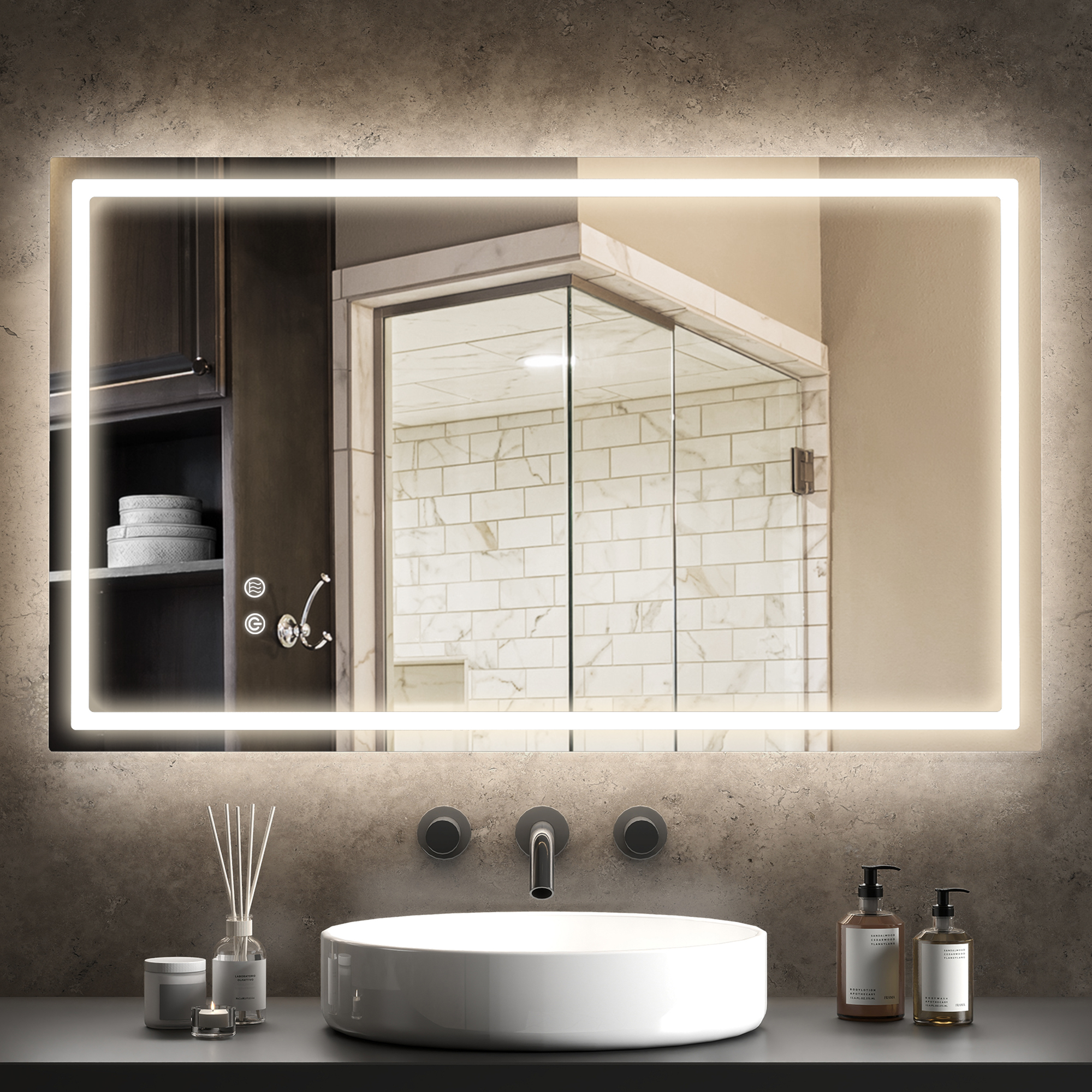 Un espejo iluminado sobre un lavabo blanco con grifo y dispensadores de jabón.