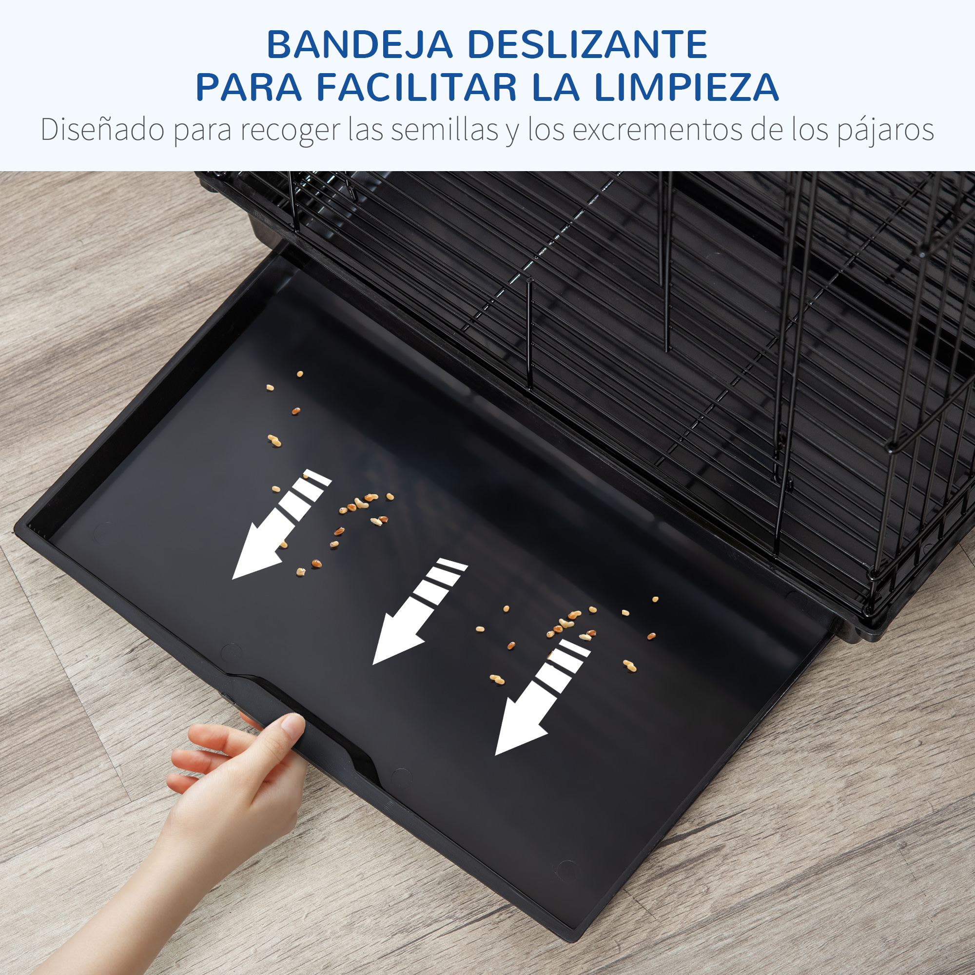 Una mano saca una bandeja negra debajo de una jaula para pájaros. Hay semillas.