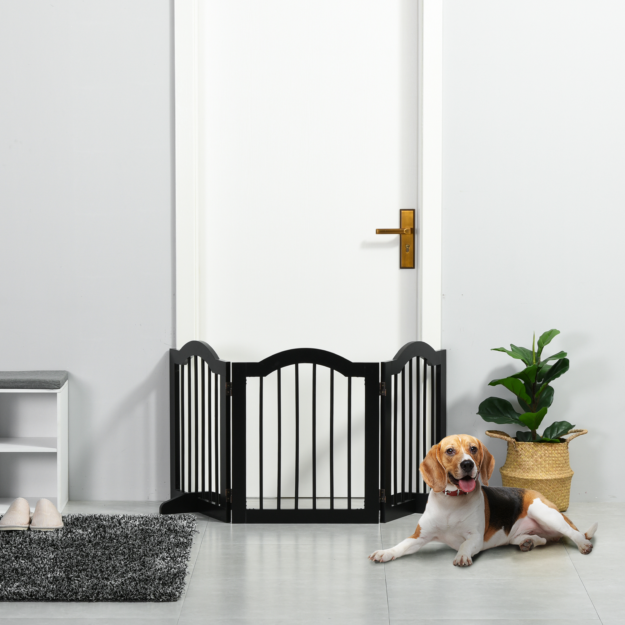 Un beagle yace junto a una barrera para mascotas negra frente a una puerta blanca.