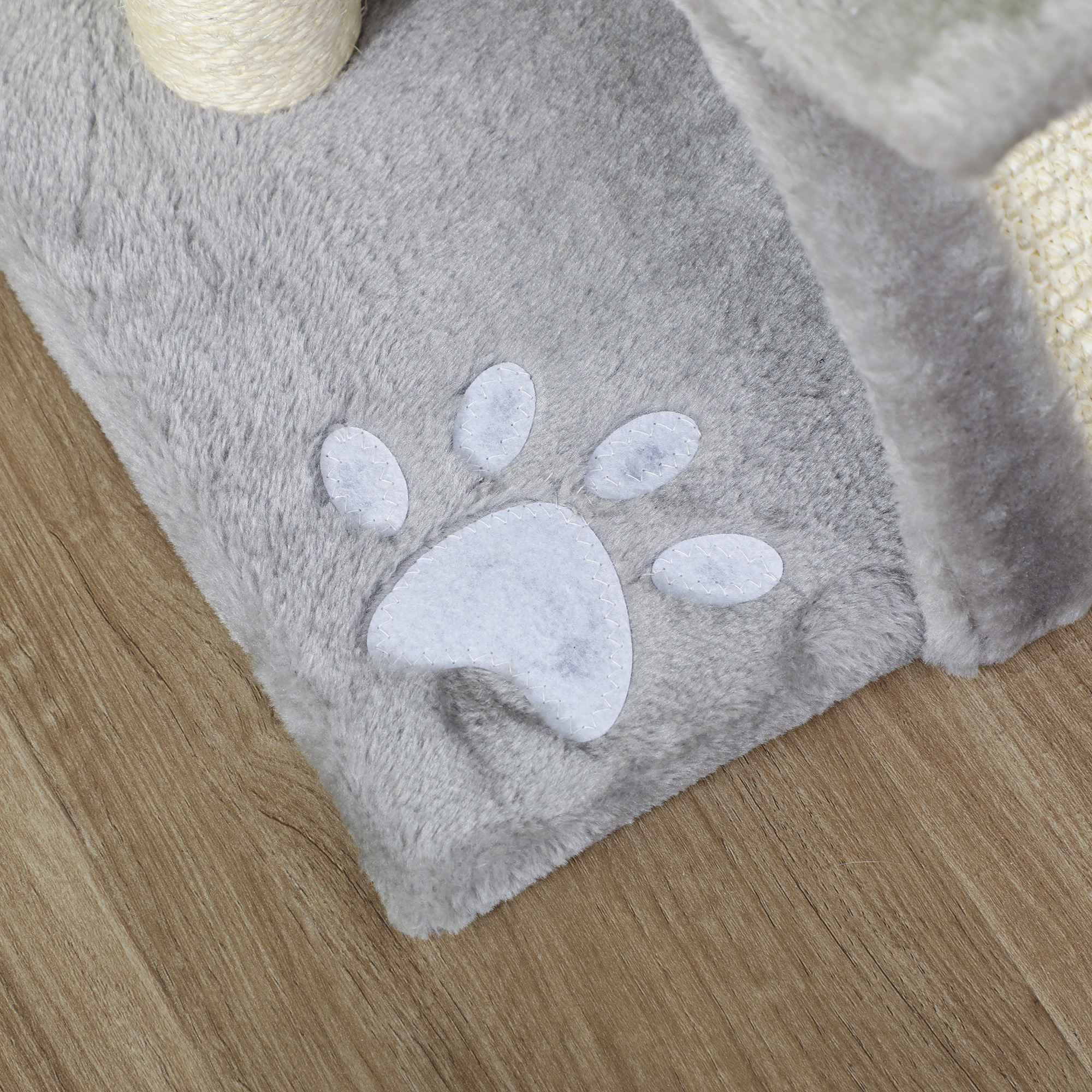 Alfombra gris con huella de pata y rollo de cuerda en suelo de madera.