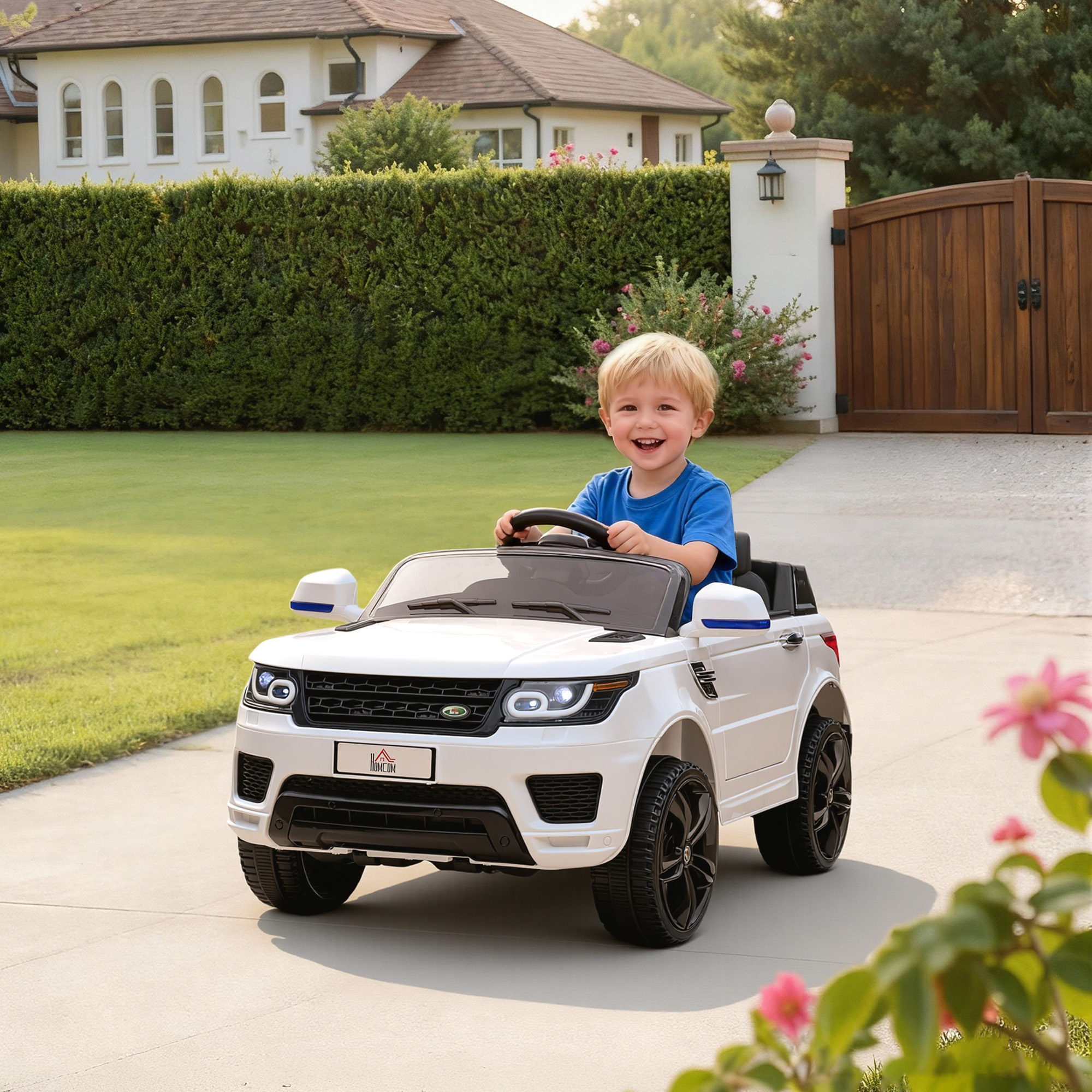 Un niño conduciendo un coche de juguete blanco en una entrada.