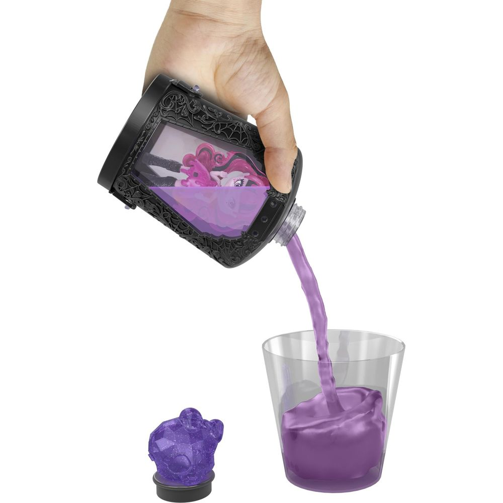 Líquido morado sale de un recipiente con muñeca a un vaso. Un cristal morado está al lado.