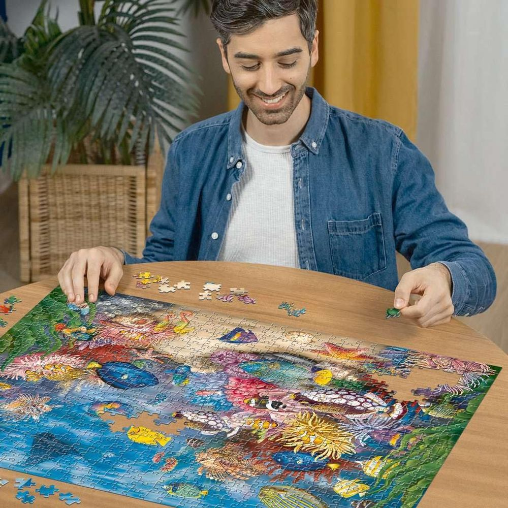 Mann puzzelt ein Unterwasserbild mit Korallen und Fischen.