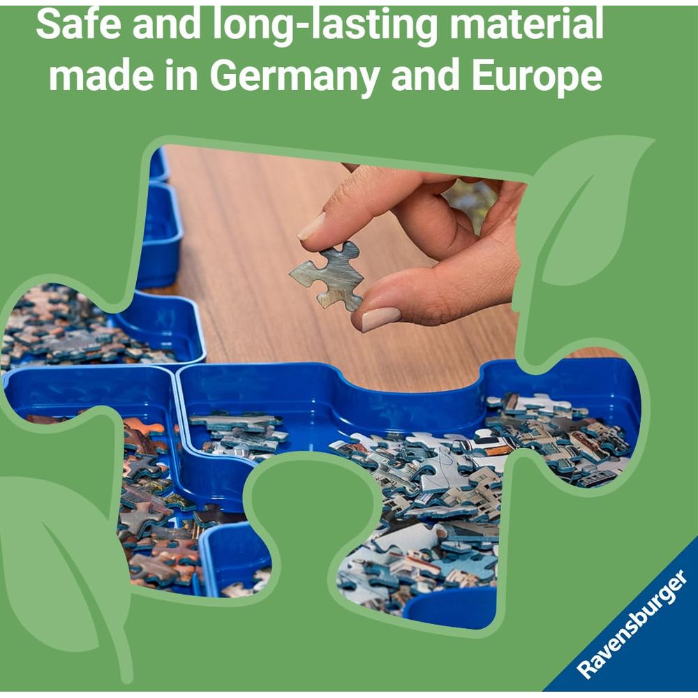 Una mano tiene un pezzo del puzzle su un vassoio blu pieno di pezzi.