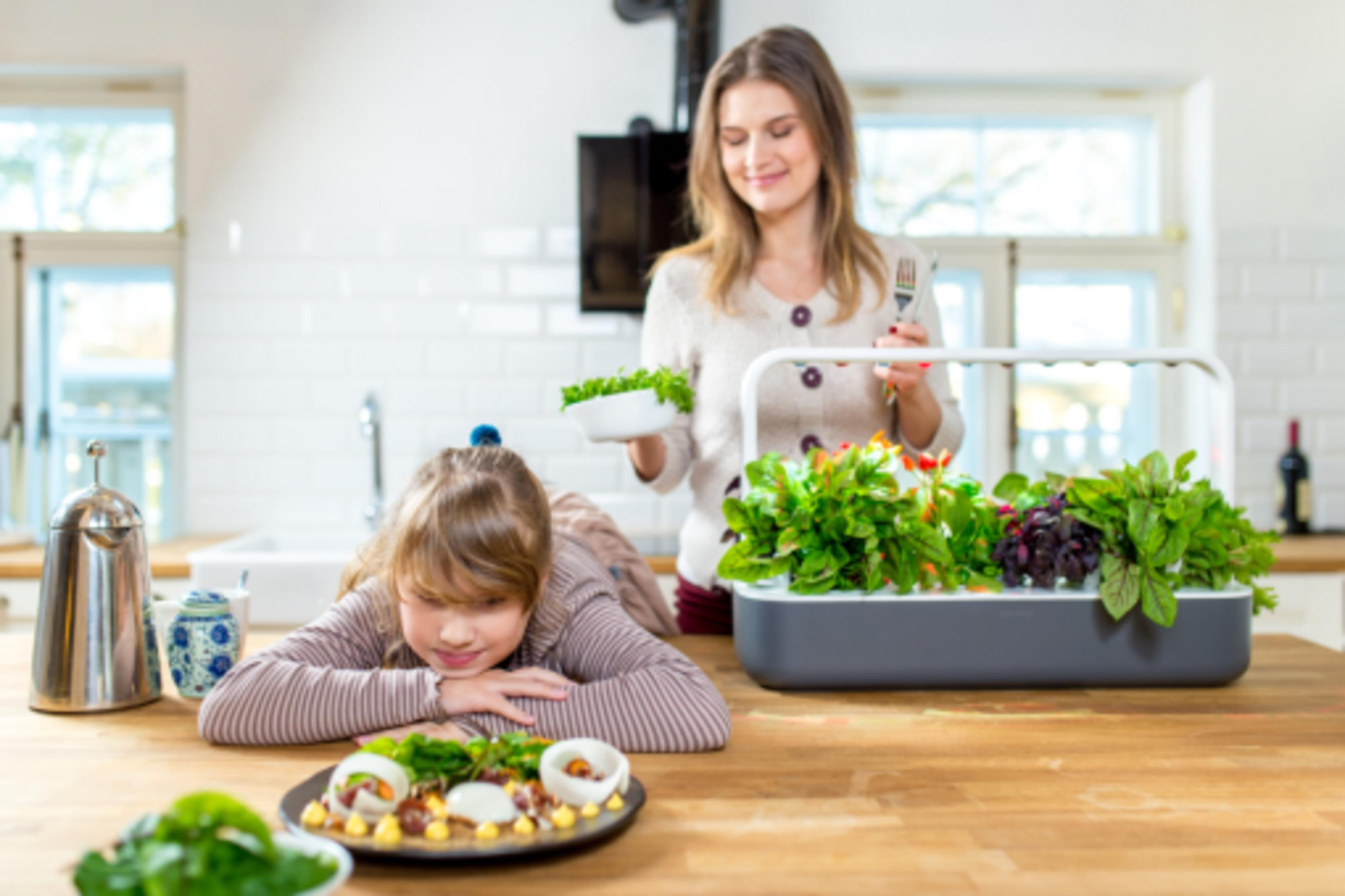 Moeder en kind in keuken met verse groenten en eten op tafel.