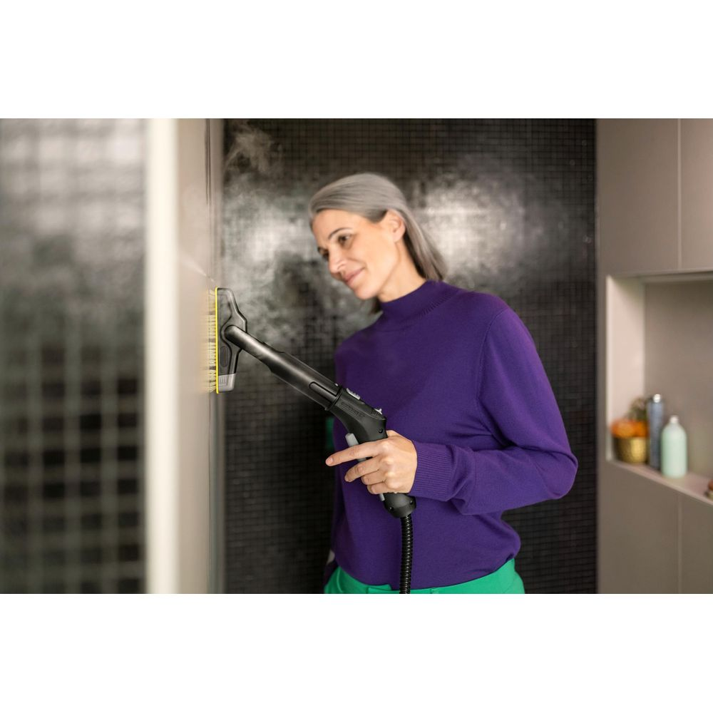 Eine Frau reinigt mit einem Dampfreiniger eine Wand.