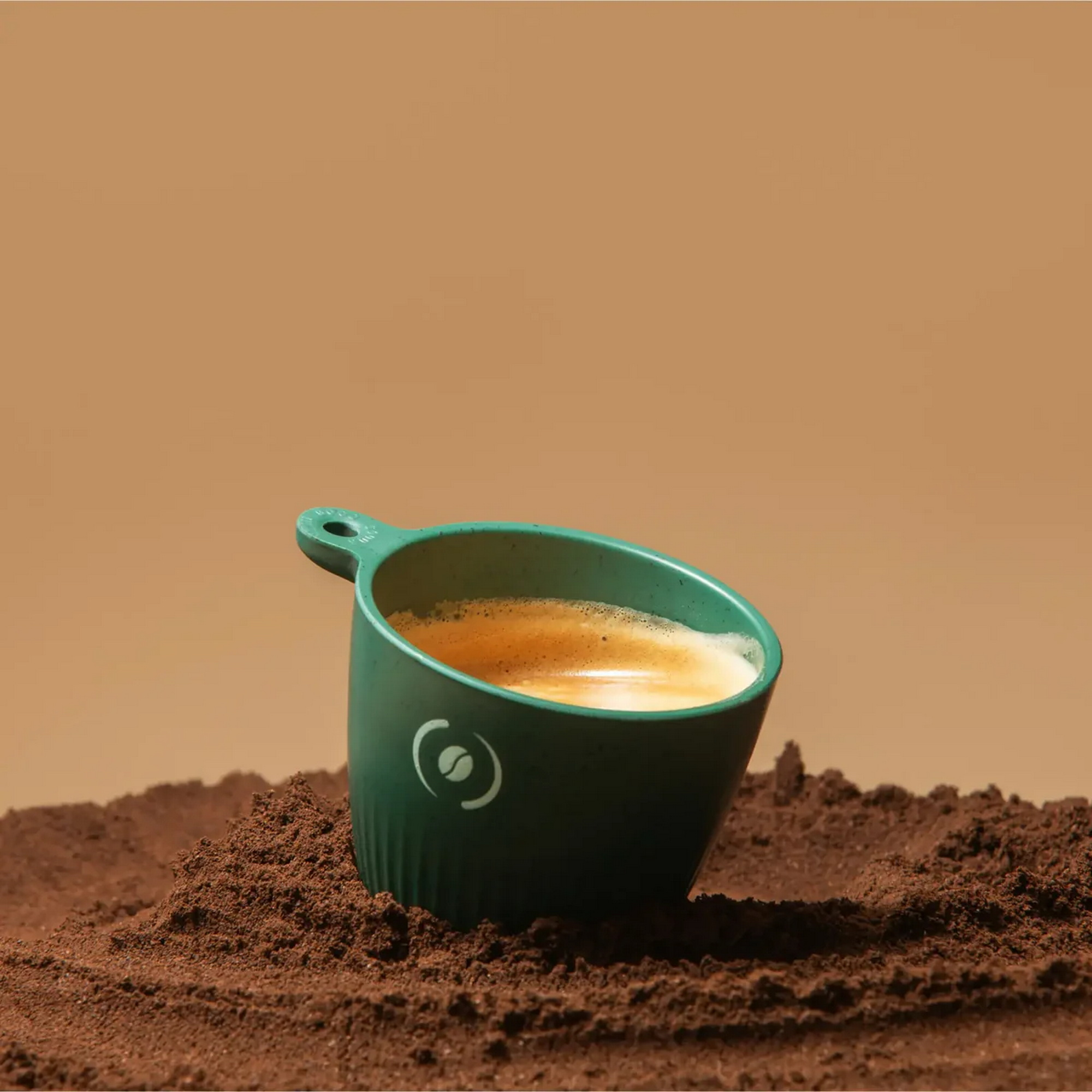 Una tazza verde di caffè è posta sul caffè macinato.
