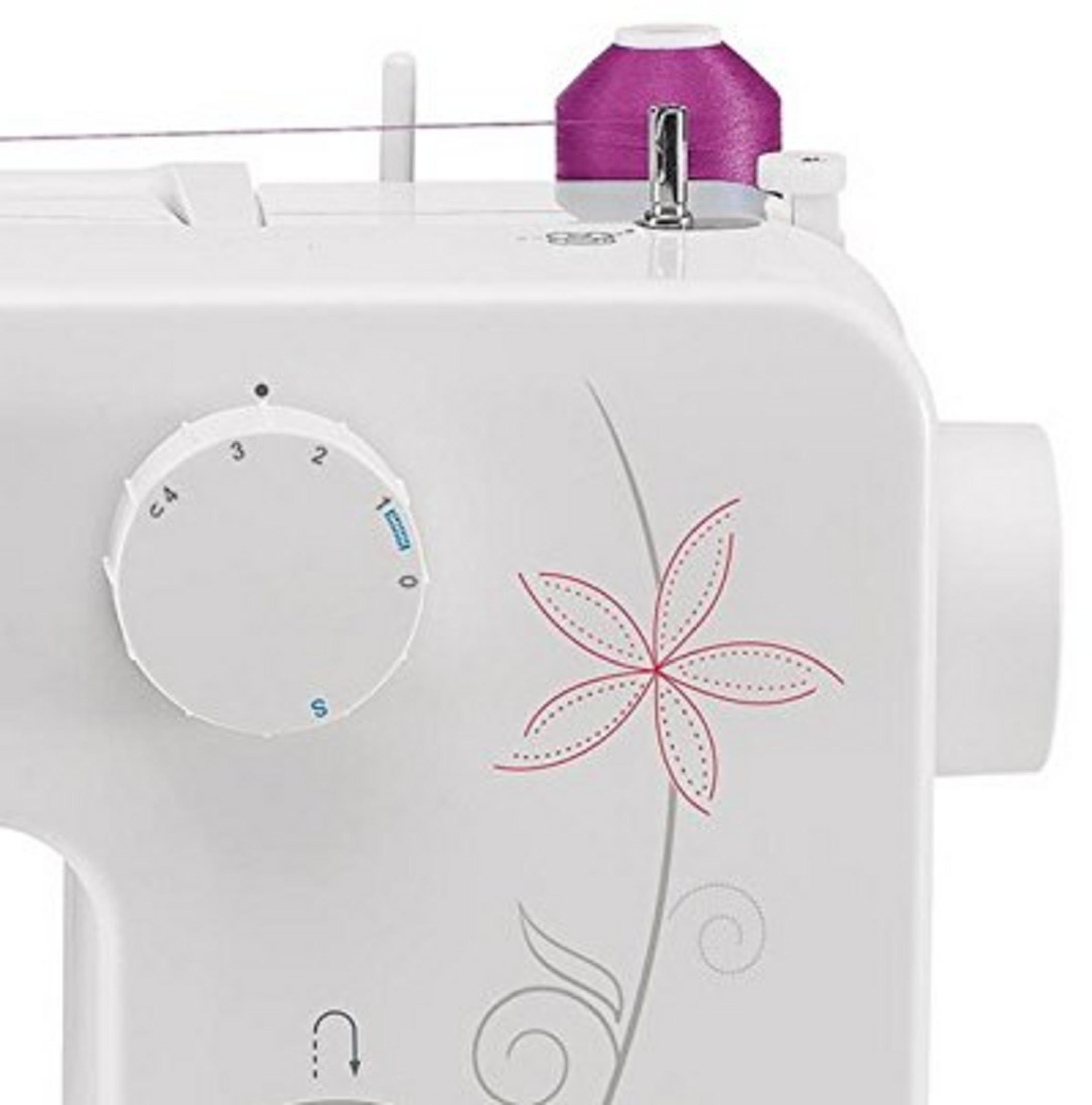 Zbliżenie białej maszyny do szycia z fioletową szpulą nici i wzorem kwiatowym.