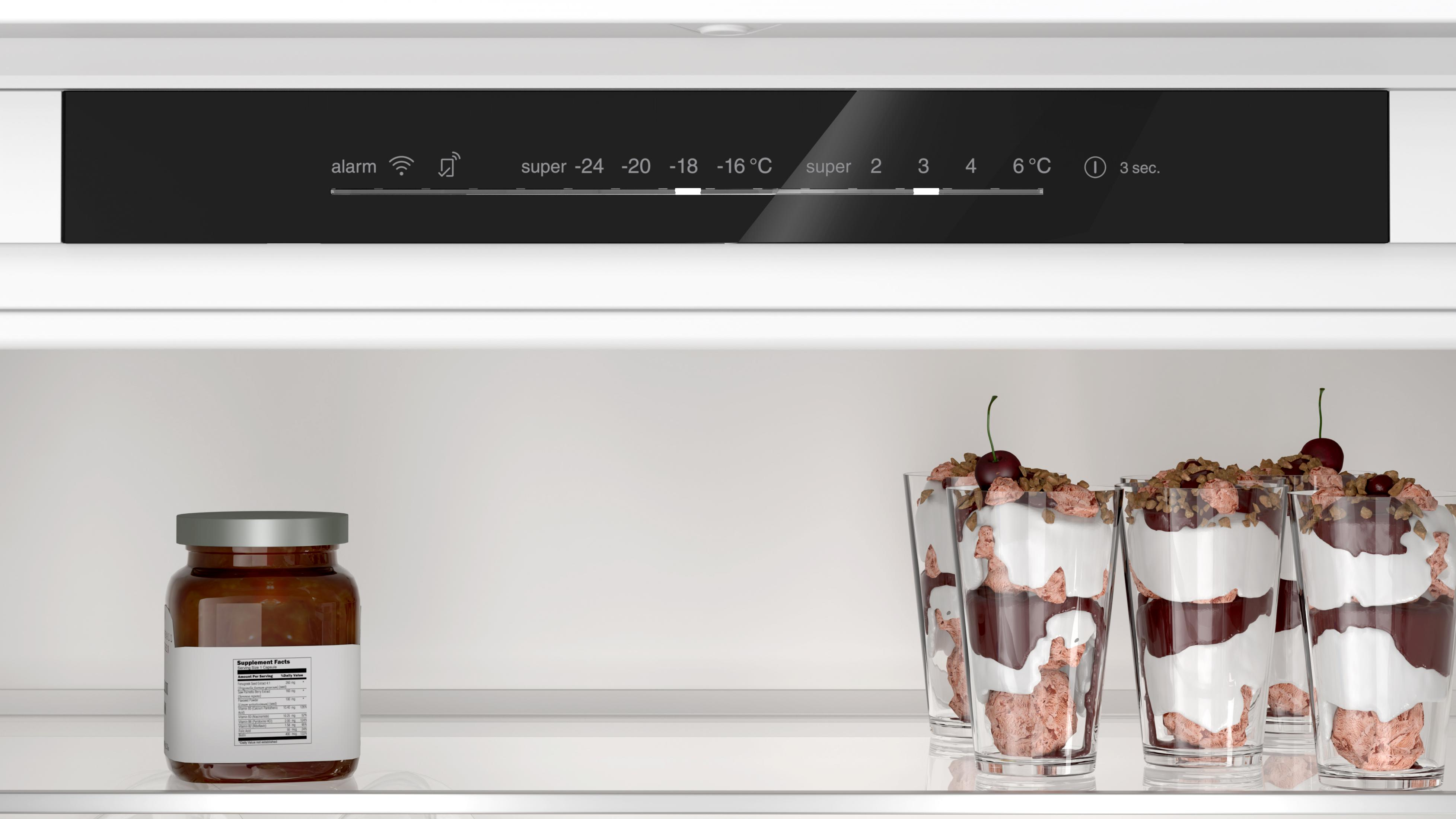 Słoik dżemu i kieliszki z parfait czekoladowym z wiśniami w lodówce.