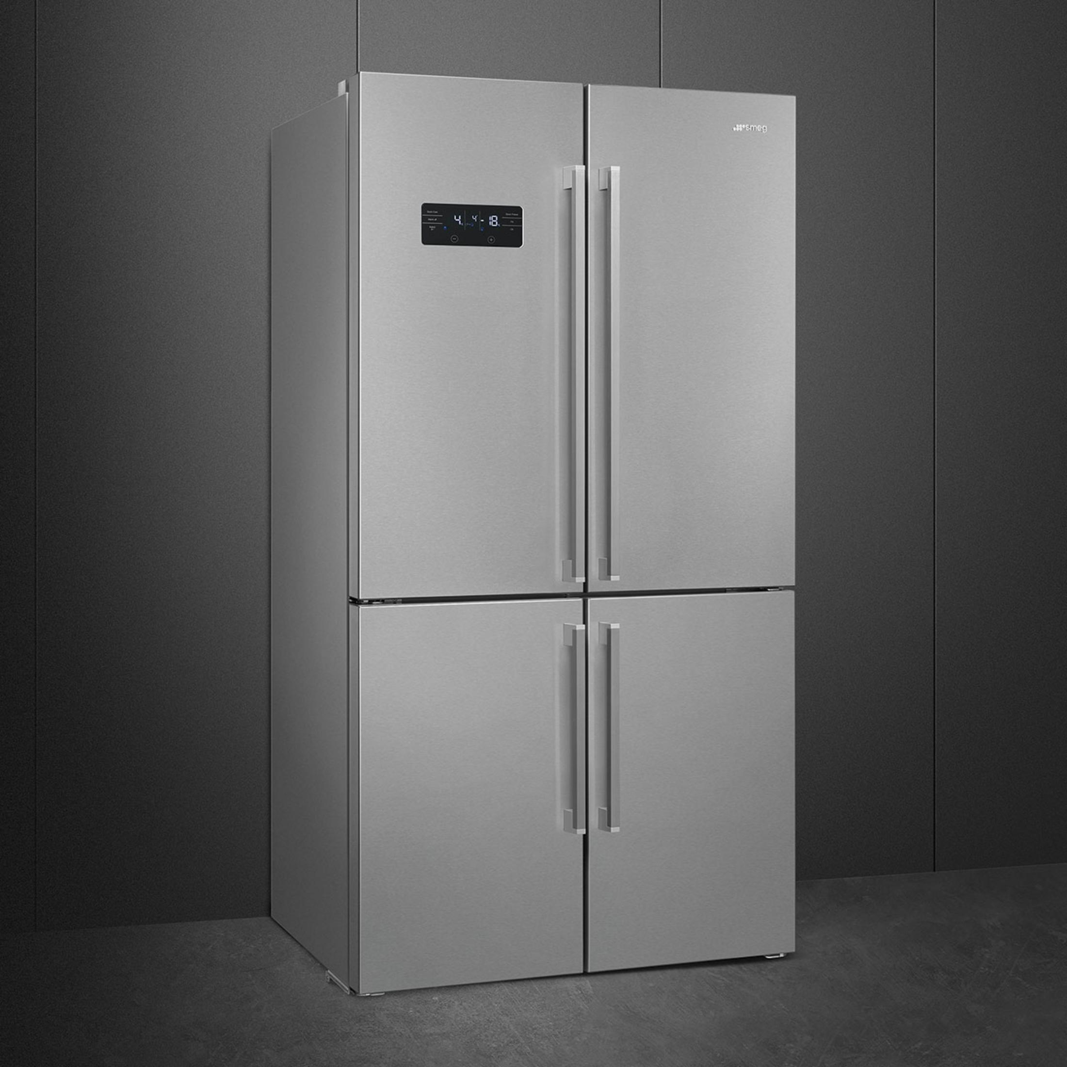 Un refrigerador plateado de cuatro puertas frente a un fondo oscuro.