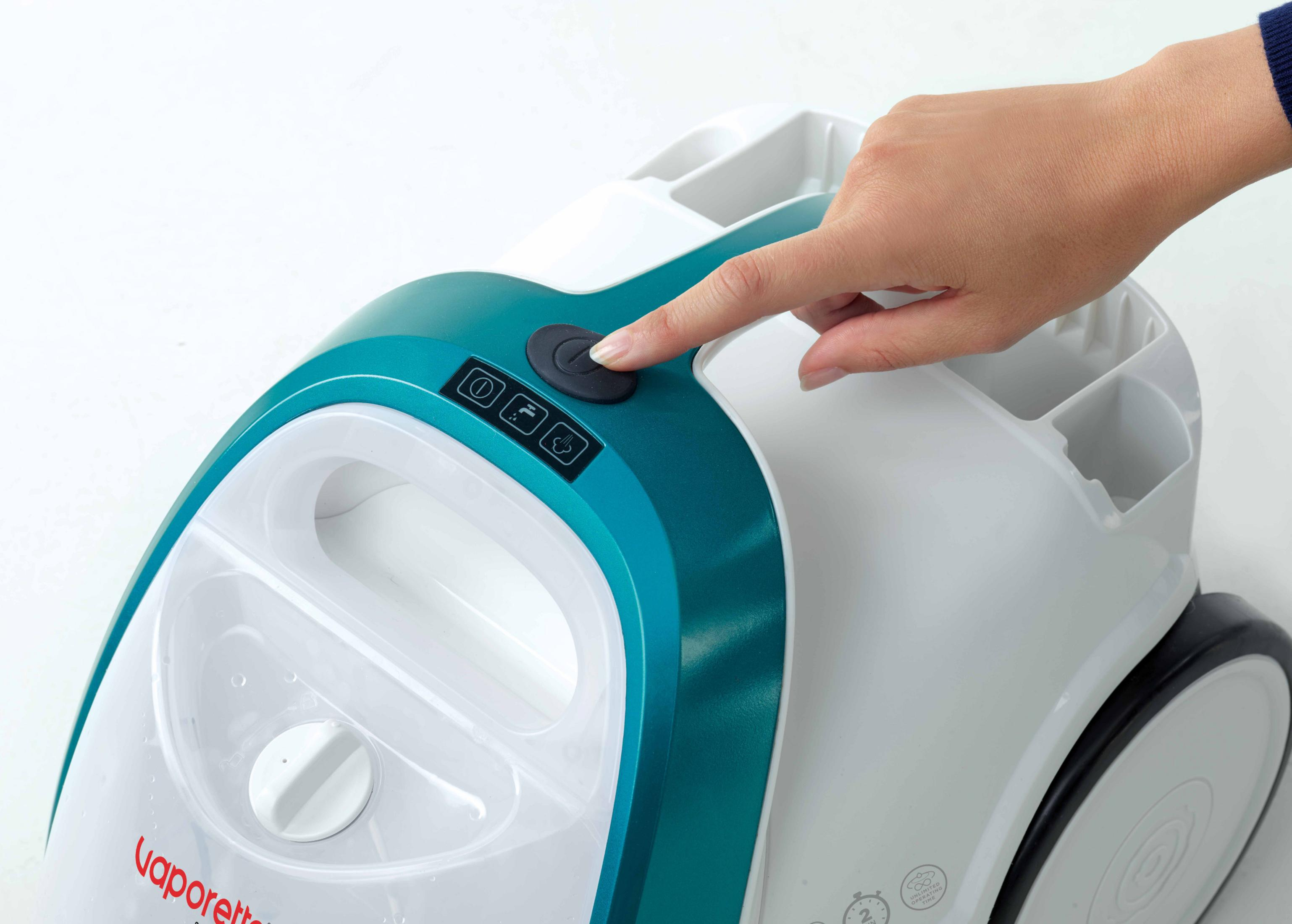 Ręka naciska przycisk zasilania na białym i turkusowym urządzeniu.