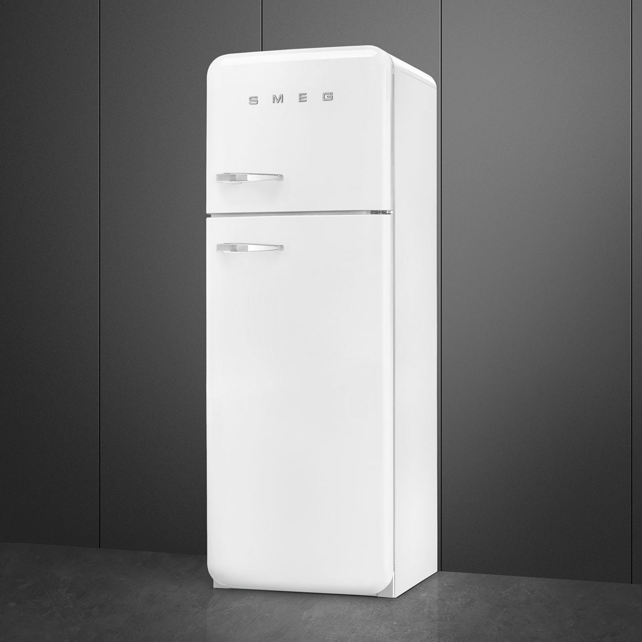 Un refrigerador SMEG blanco con tiradores plateados sobre suelo oscuro.