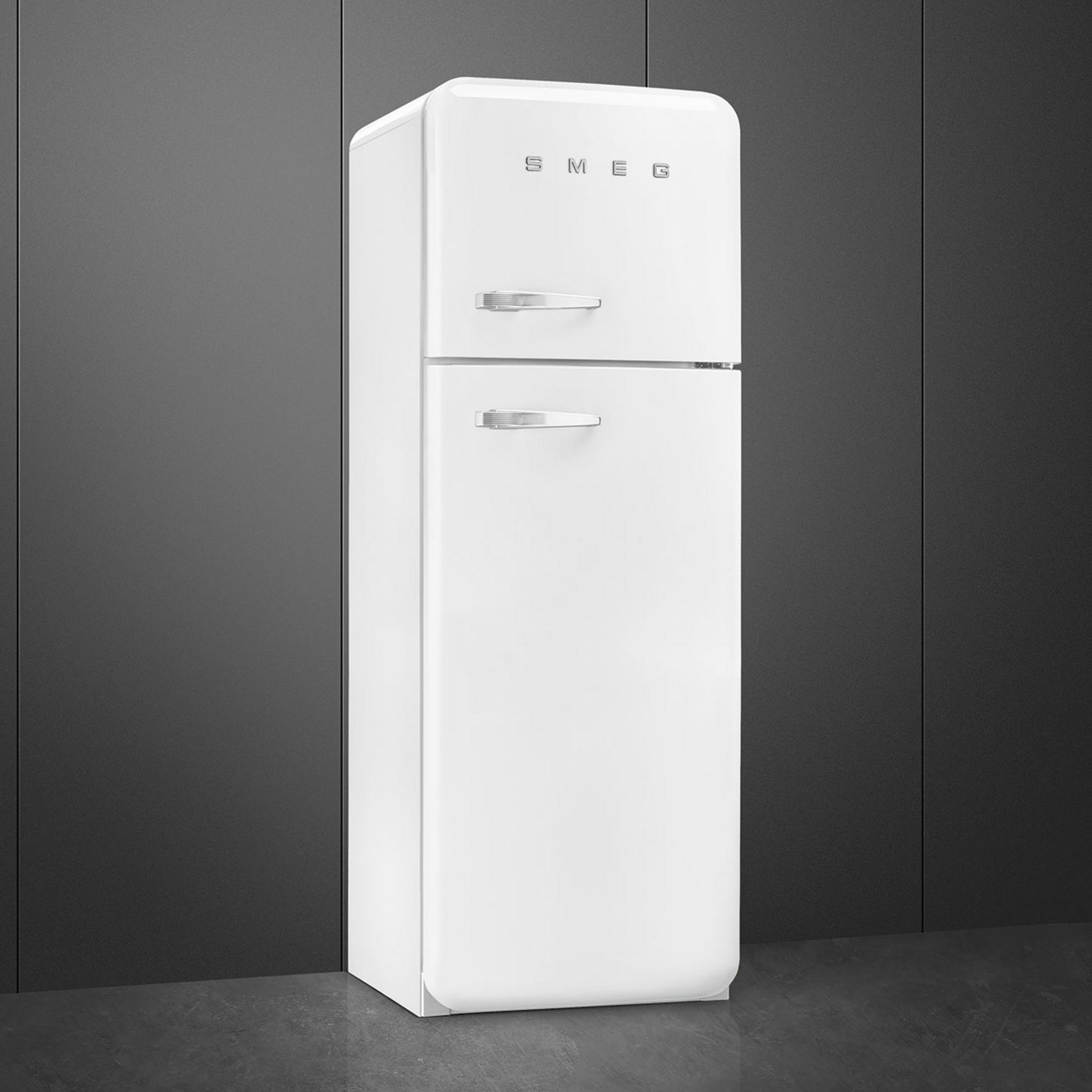 Un refrigerador blanco SMEG con tiradores plateados sobre suelo oscuro.