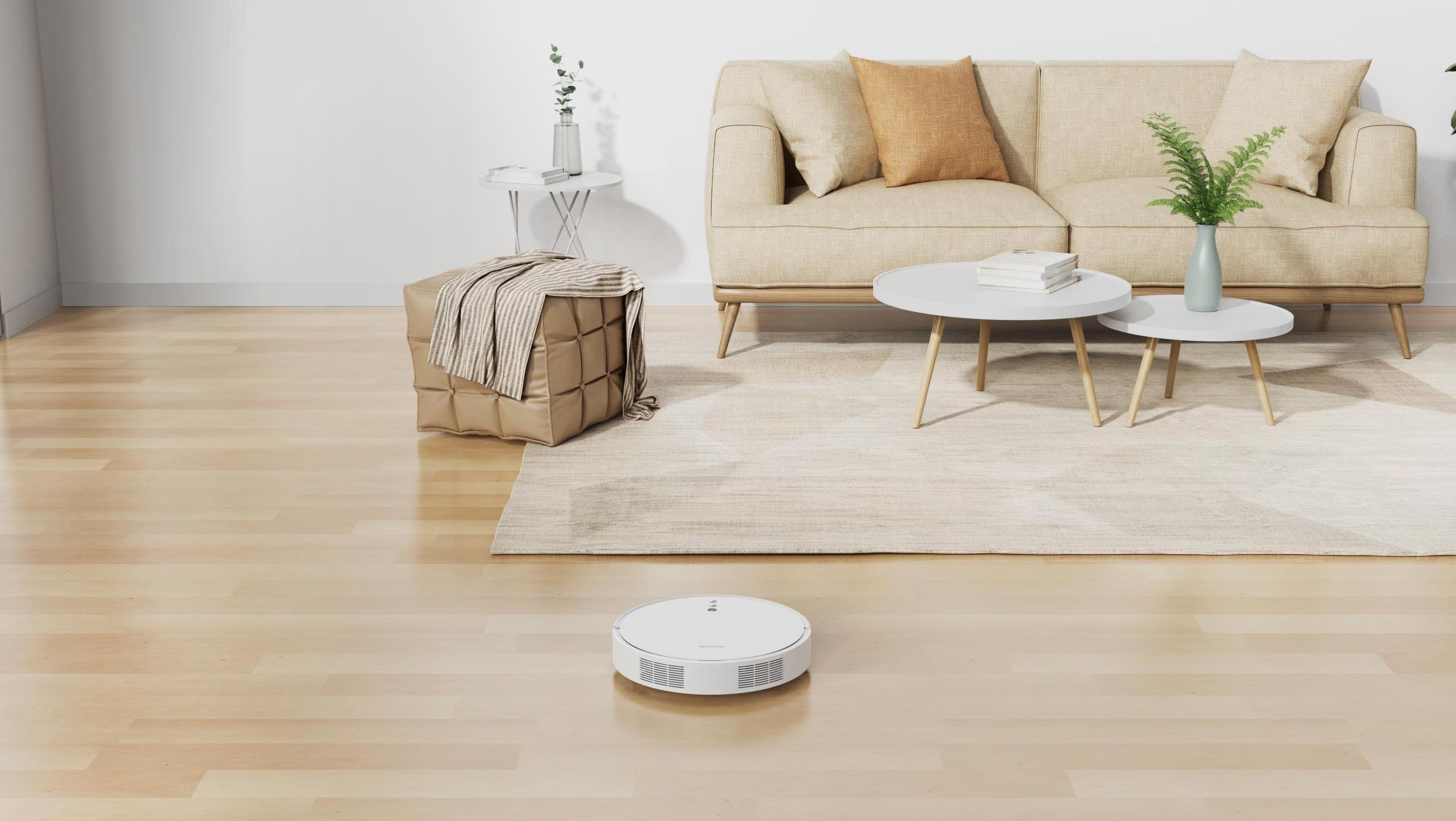 Un robot aspirador blanco limpia un suelo de madera en un salón moderno.