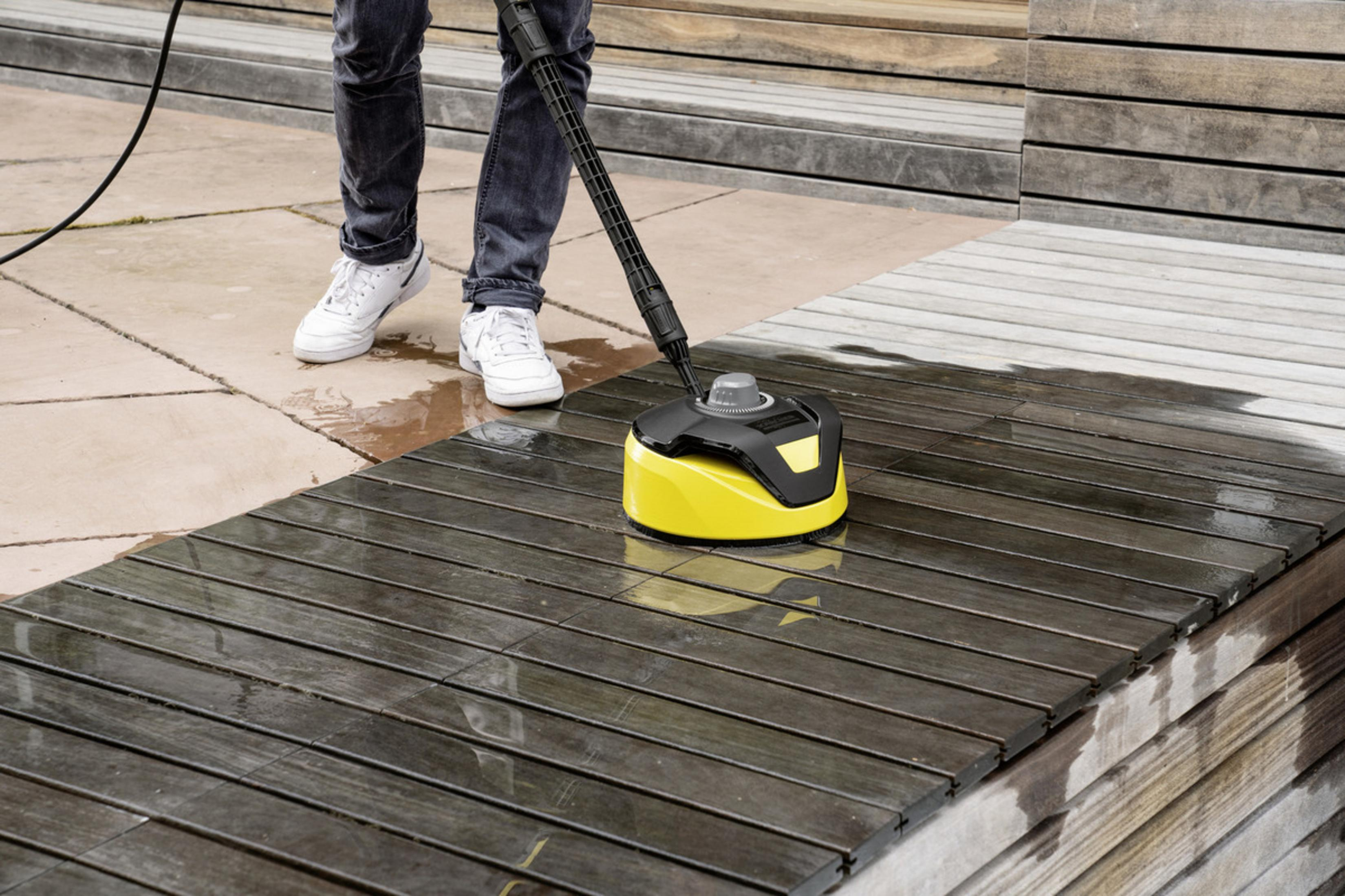 Una persona pulisce un ponte di legno con un'idropulitrice.