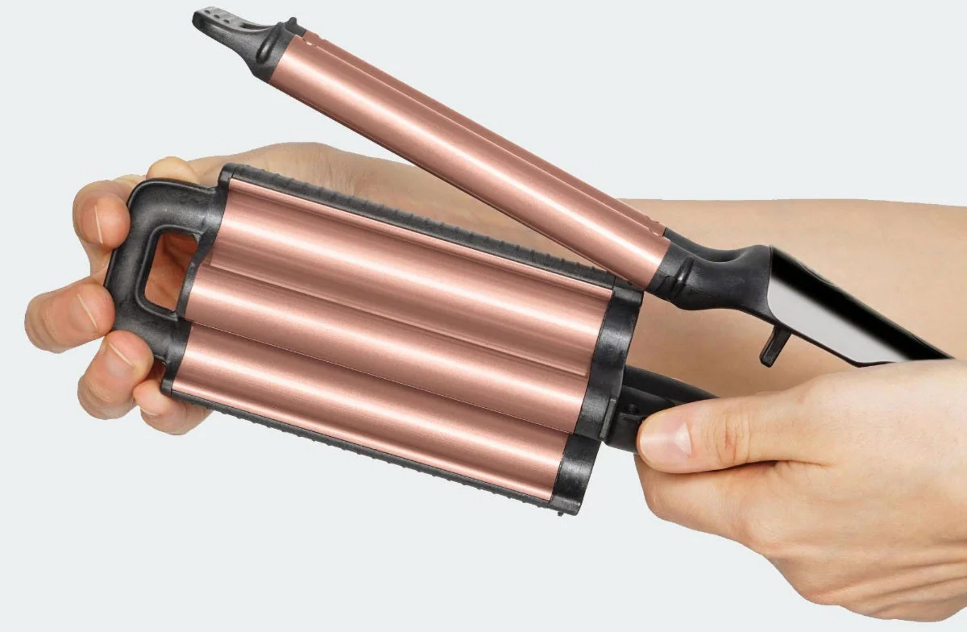 Dłonie trzymające różowo-złotą falownicę z czarnymi uchwytami.