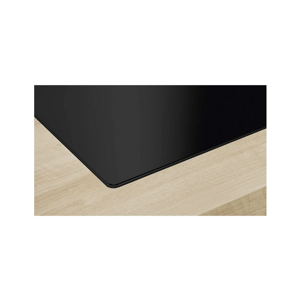 Zbliżenie czarnej płyty grzewczej na jasnym drewnie