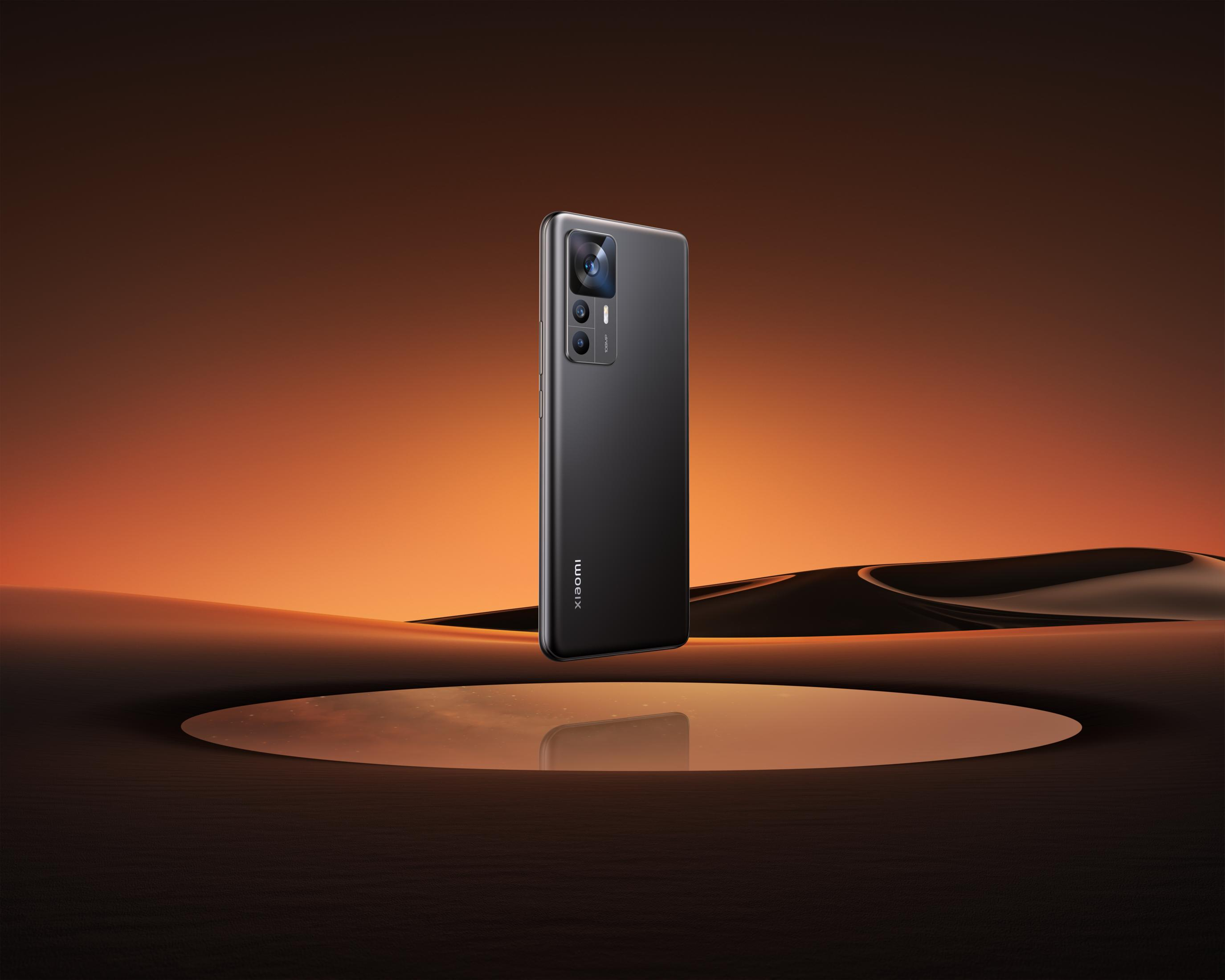 Czarny smartfon unosi się nad pustynnym odbiciem o zachodzie słońca.