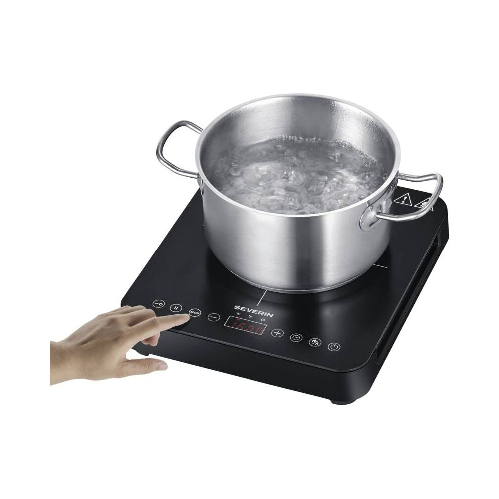 Garnek gotującej się wody stoi na czarnej płycie indukcyjnej obsługiwanej przez rękę.