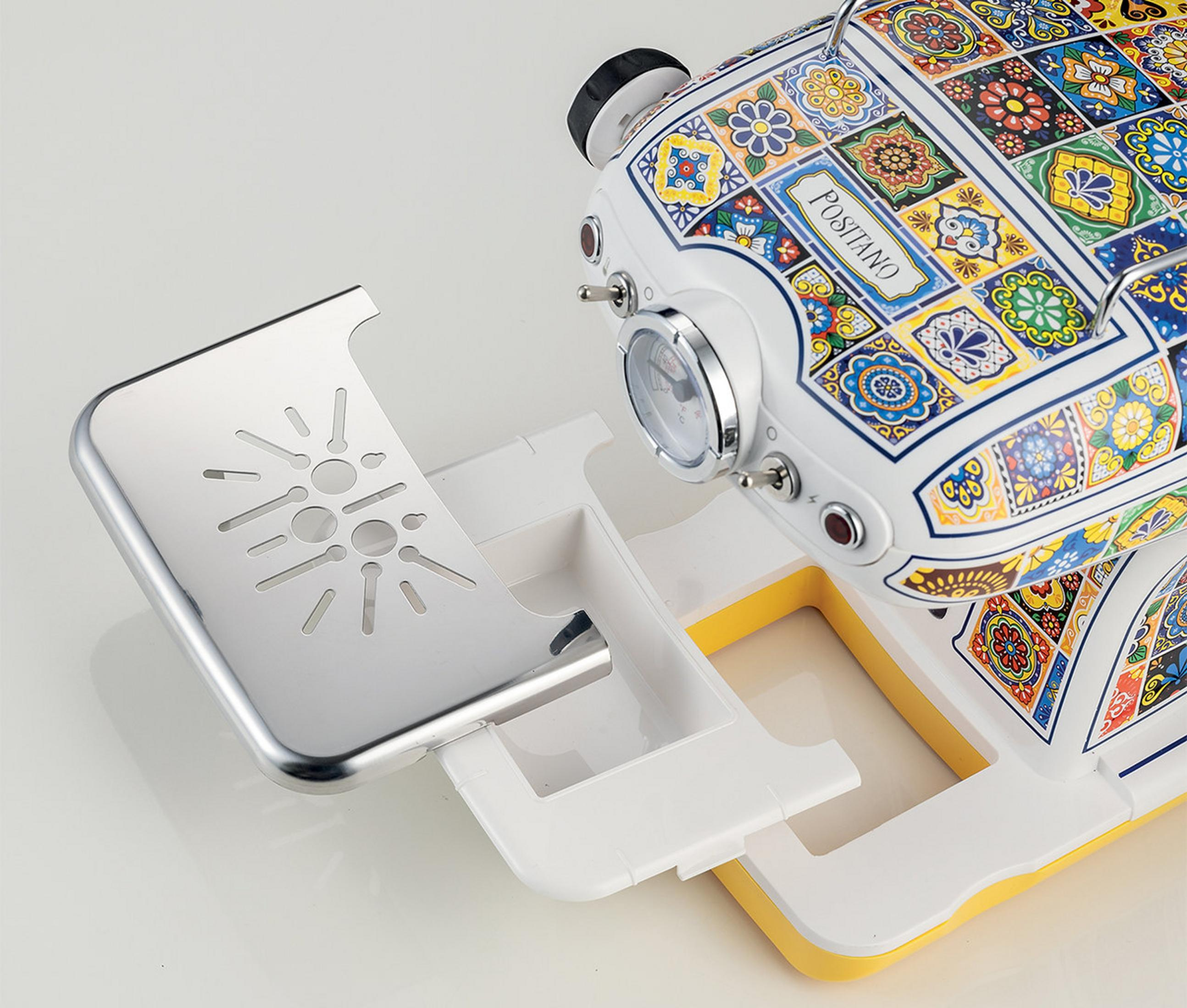 Biała maszyna do kawy z kolorowymi wzorami płytek i chromowaną tacką ociekową.
