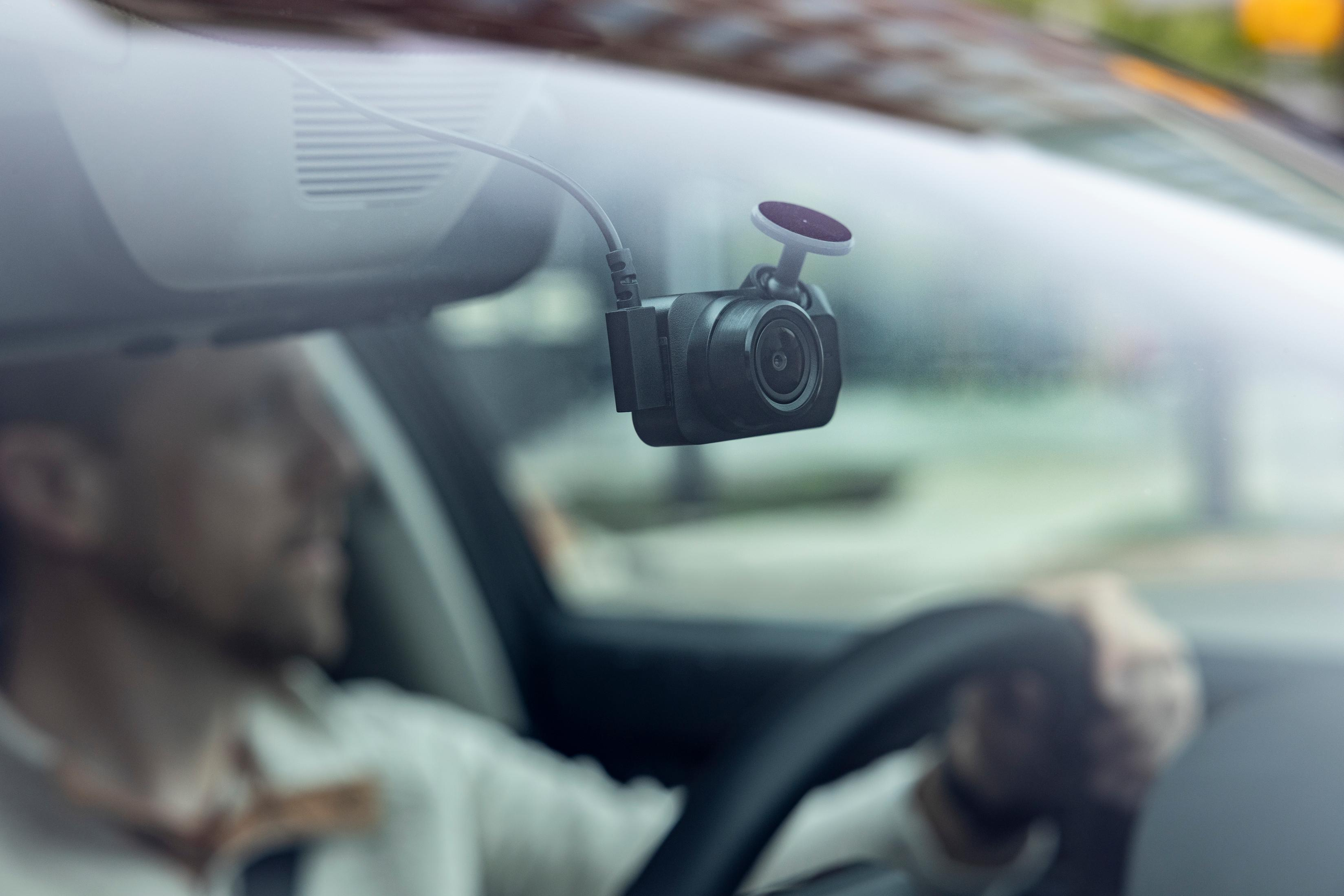 Fahrer im Auto mit Dashcam an der Windschutzscheibe.