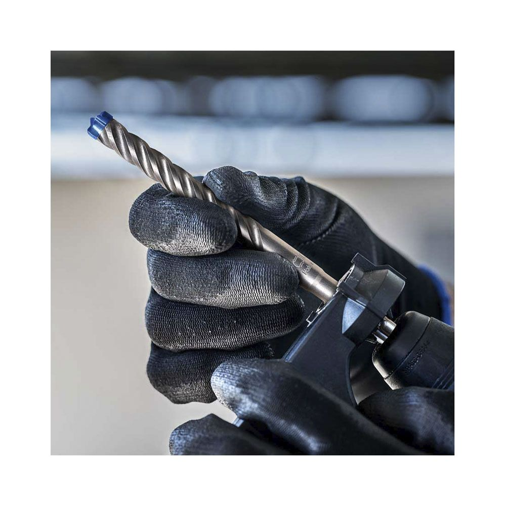 Mit Handschuhen wird ein Bohrer mit blauer Spitze gehalten.