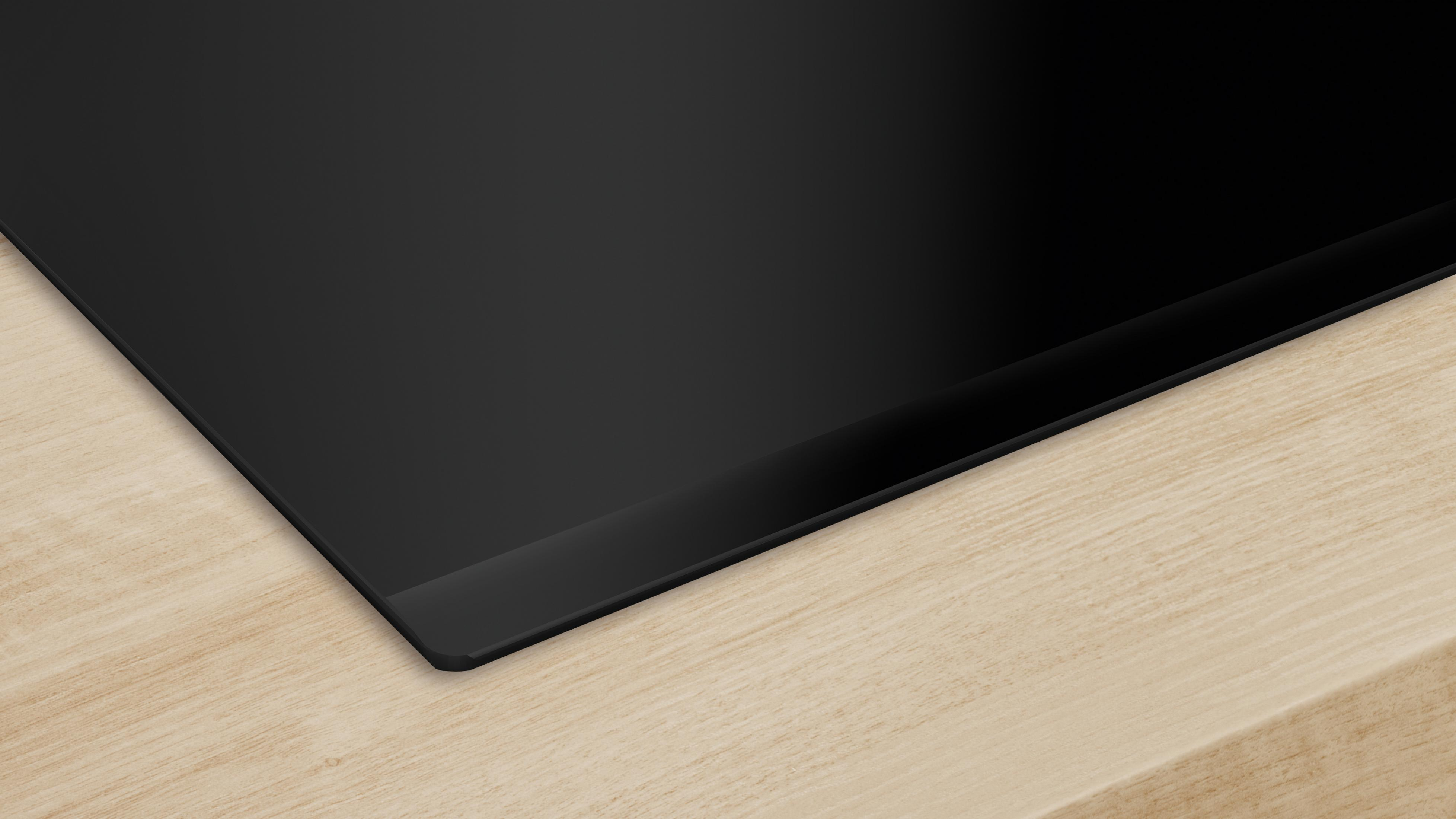 Czarna płyta szklana spoczywa na drewnianej powierzchni.