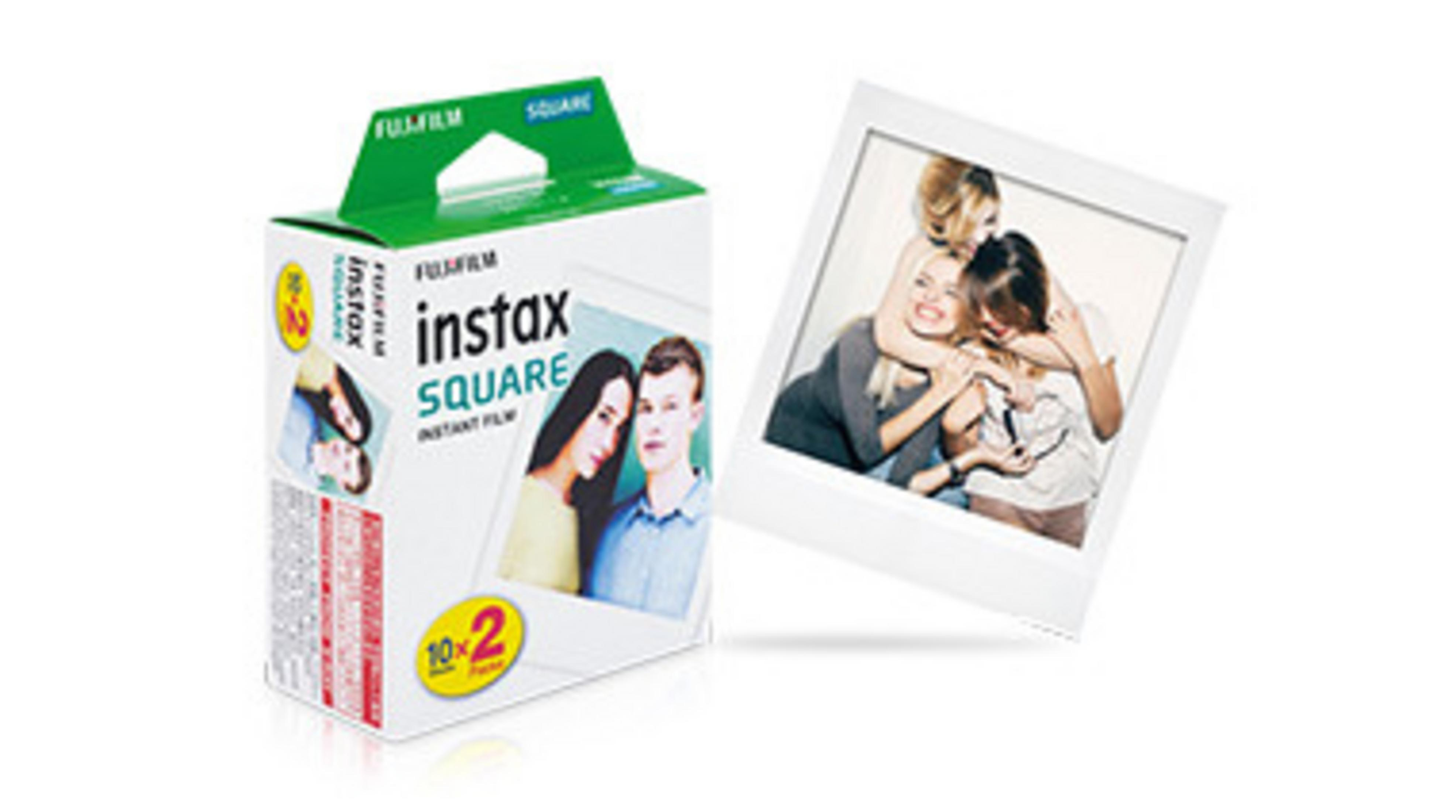 Pudełko filmu Fujifilm Instax Square obok oprawionego zdjęcia natychmiastowego trzech uśmiechniętych młodych kobiet.