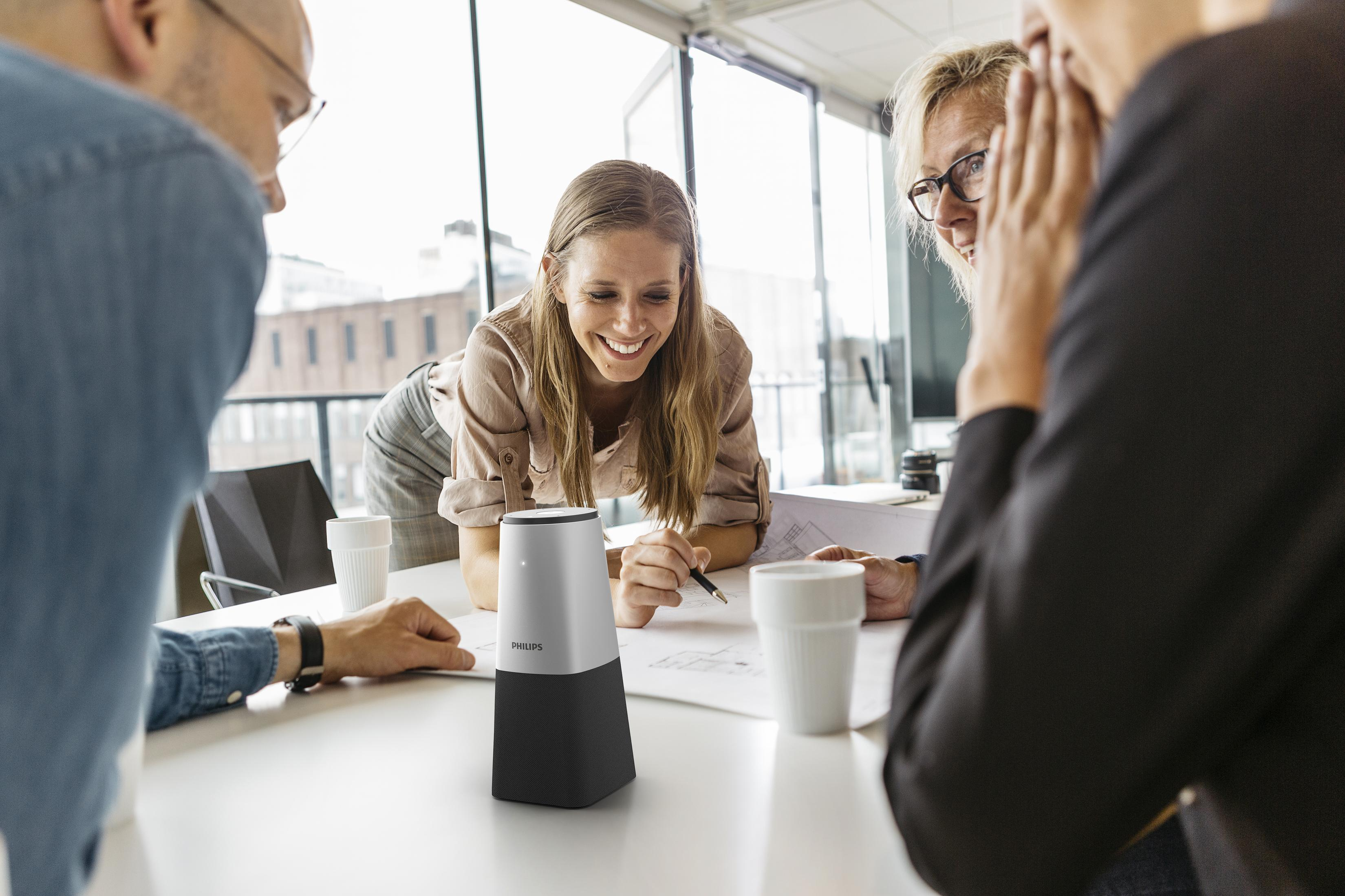 Persone in un ufficio attorno a un tavolo con dispositivo Philips e tazze.