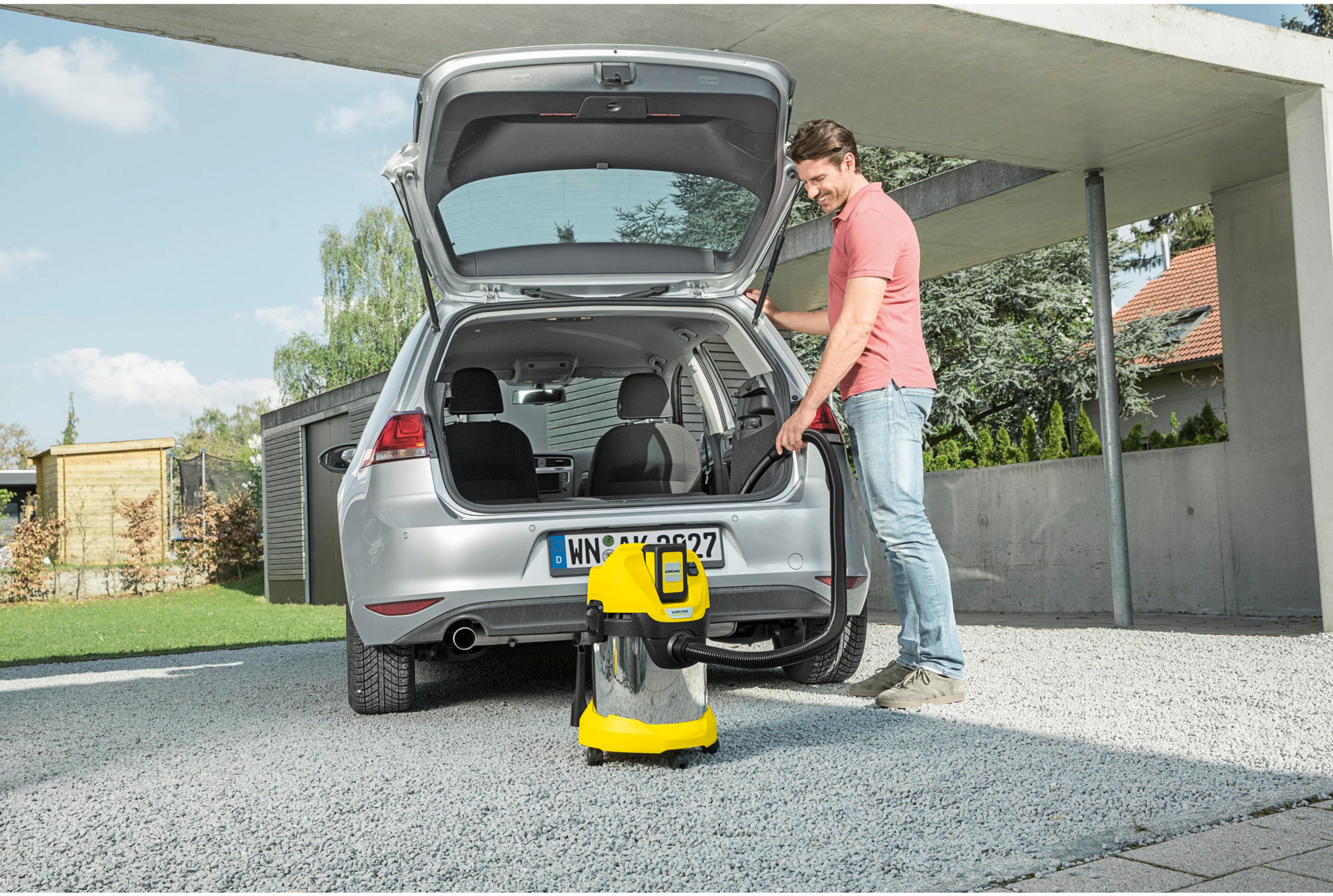 Homme nettoie voiture avec aspirateur Kärcher en extérieur.