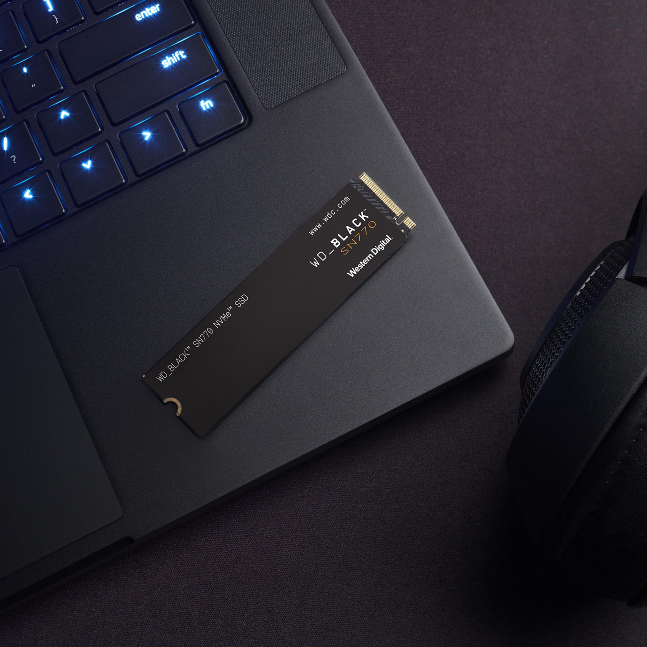 Un SSD noir repose sur un clavier rétroéclairé, avec des écouteurs à proximité.