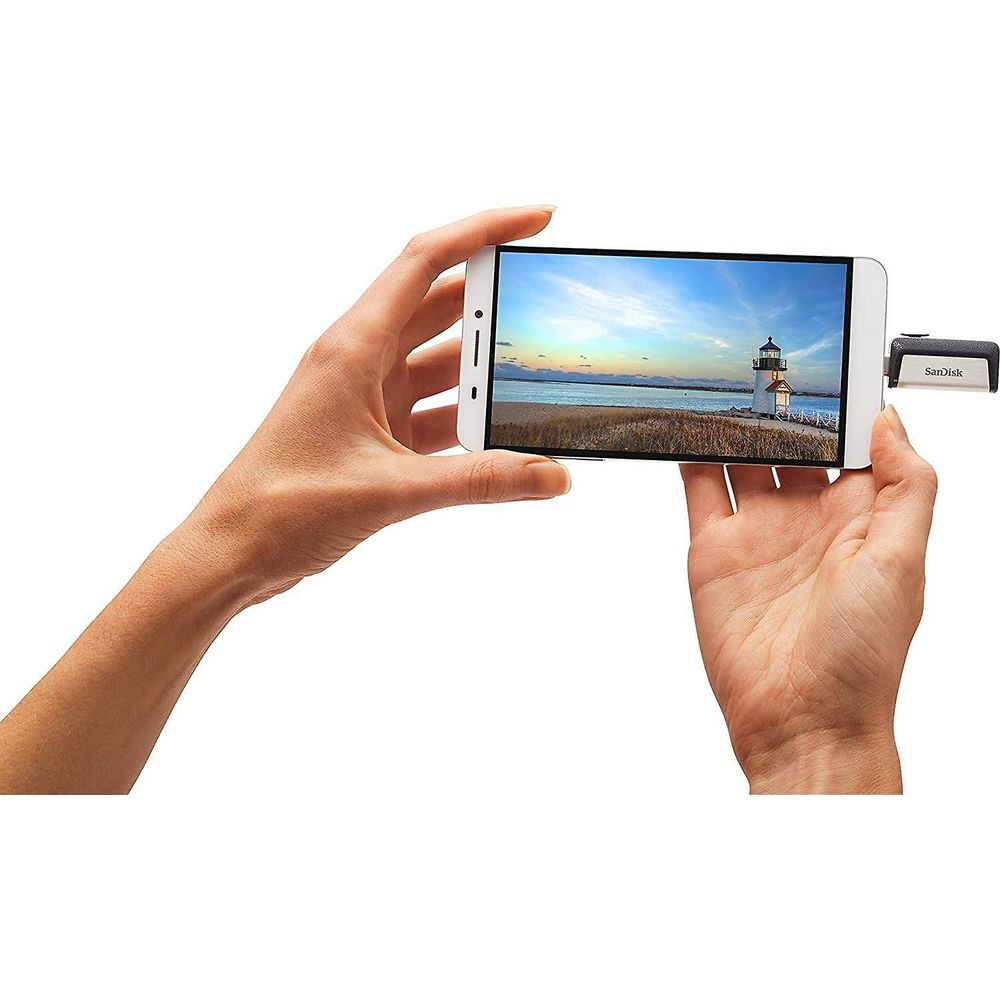 Dwie ręce trzymają smartfon z latarnią morską nad morzem.