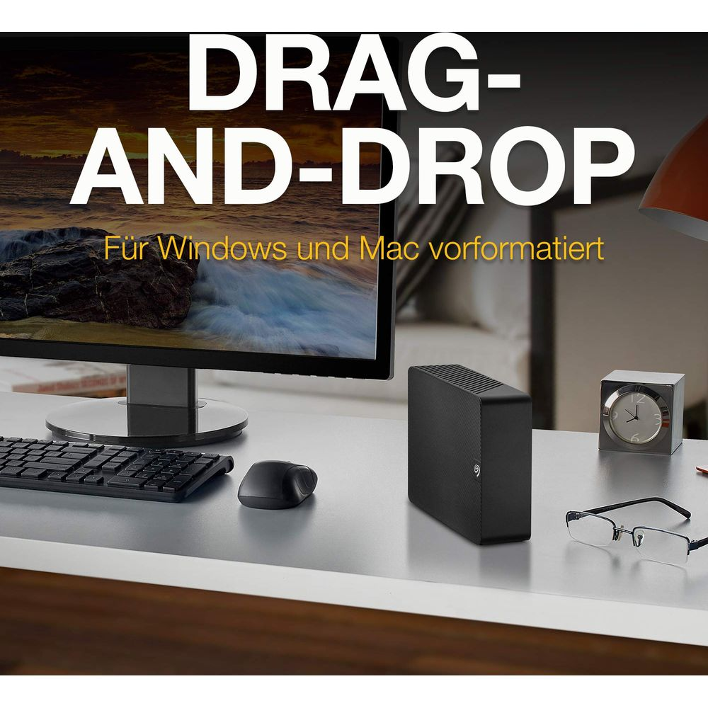 Biurko z monitorem, klawiaturą, myszą, zewnętrznym dyskiem twardym i okularami.