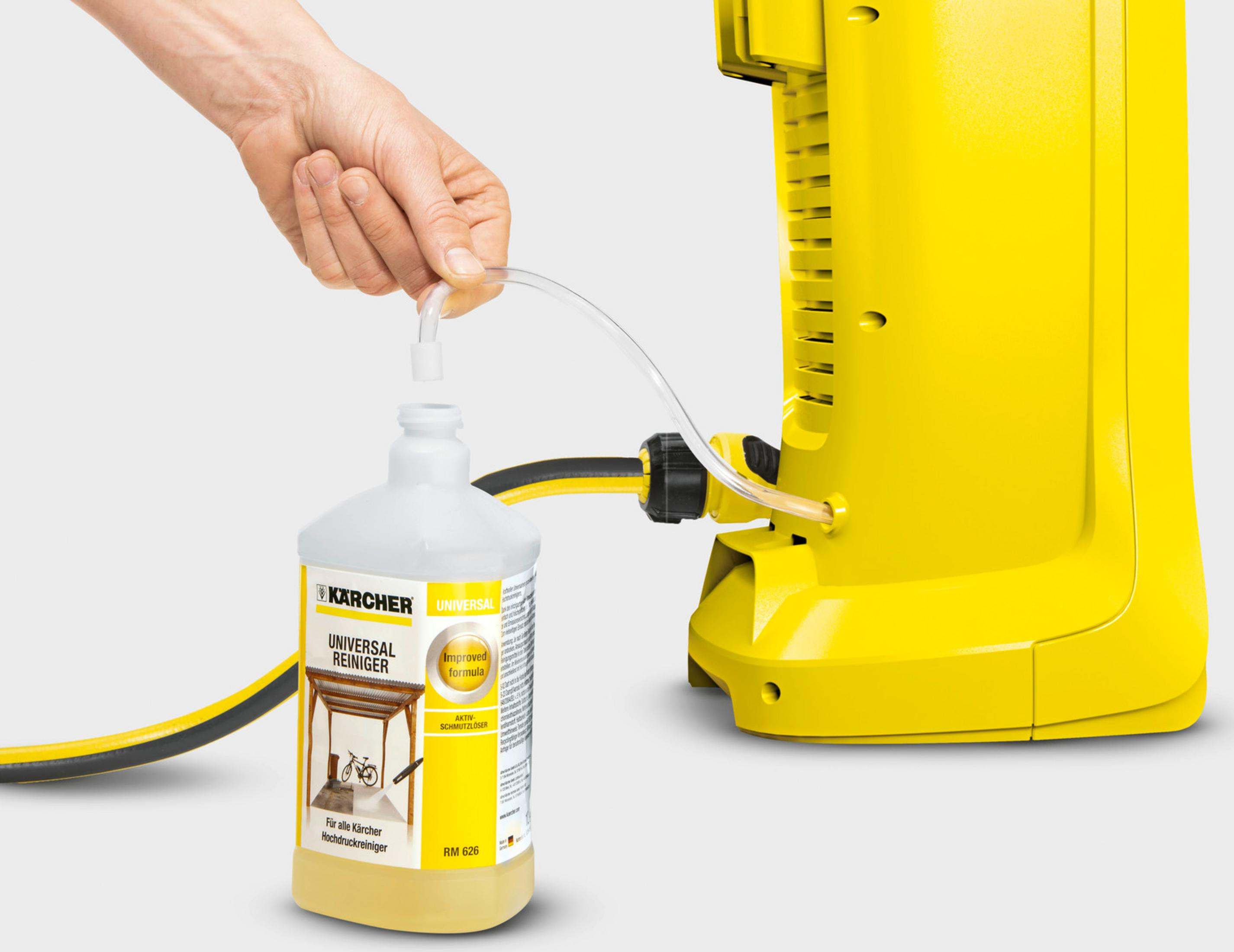 Una mano tiene un tubo in una bottiglia di detergente Karcher giallo.
