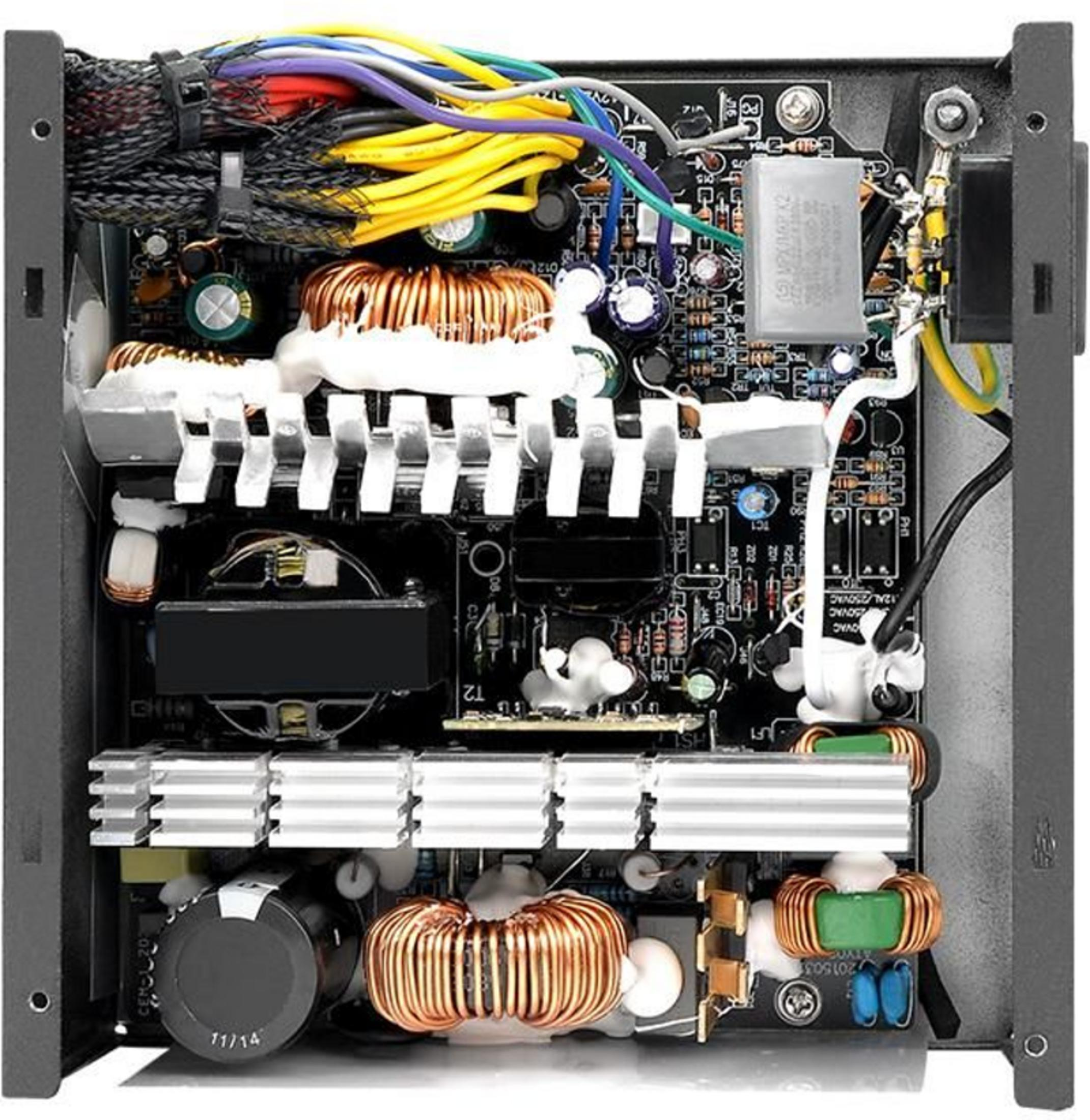 Interior de fuente de alimentación: cables, bobinas, condensadores, disipadores y placa.
