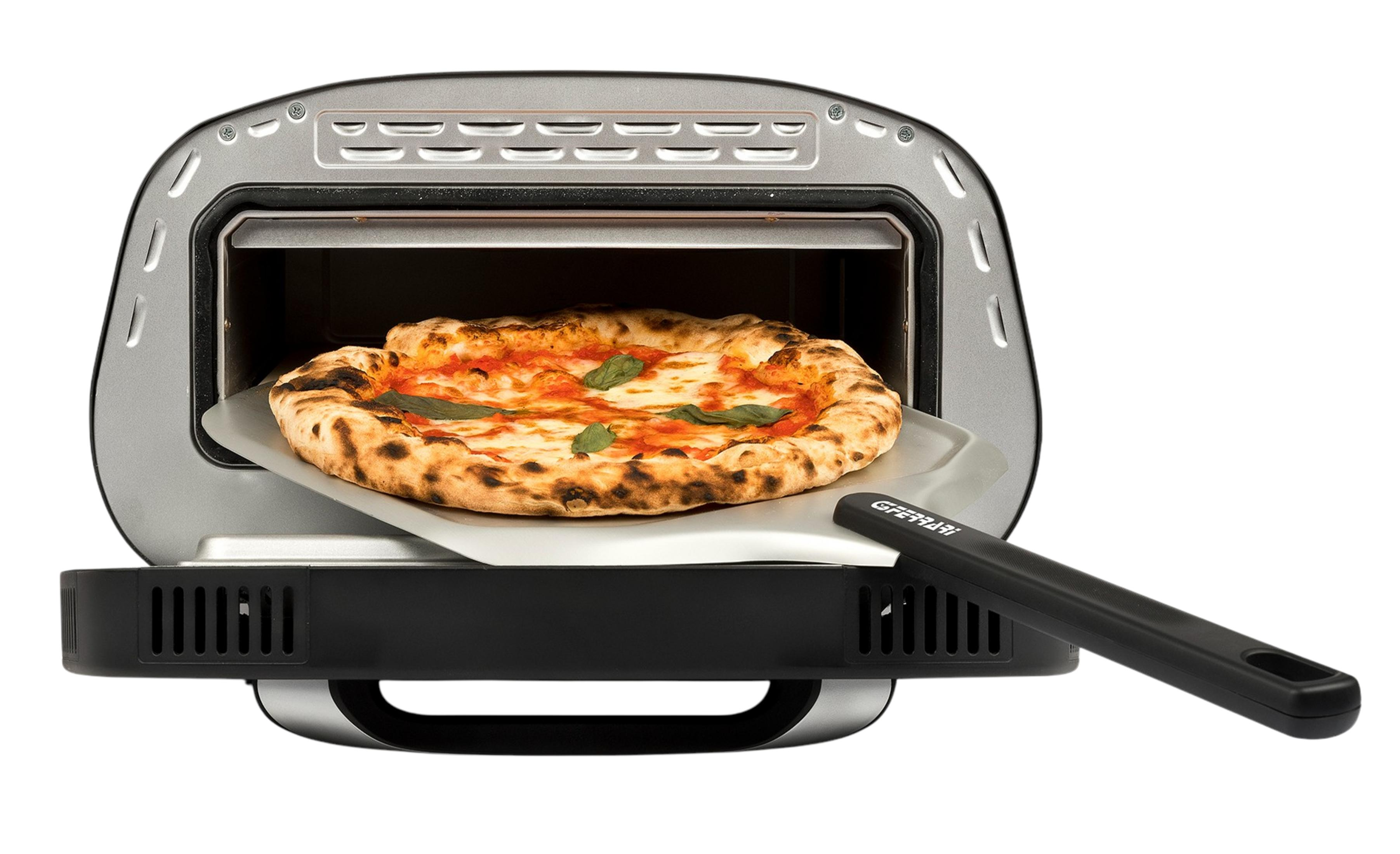Una pizza rotonda con pomodoro, formaggio e basilico viene tolta da un forno.