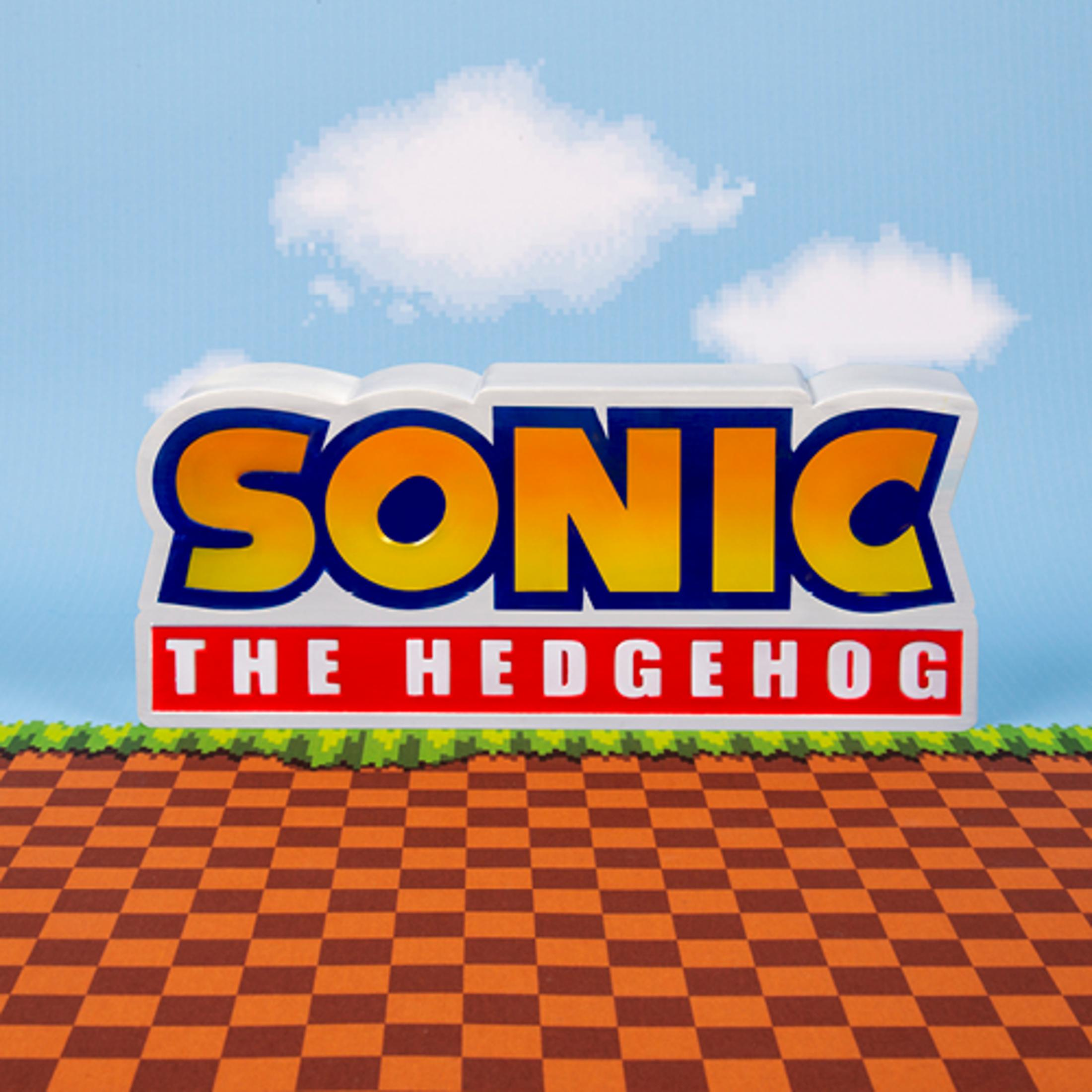 Logo Sonic the Hedgehog devant un ciel pixelisé et un sol à damier marron.