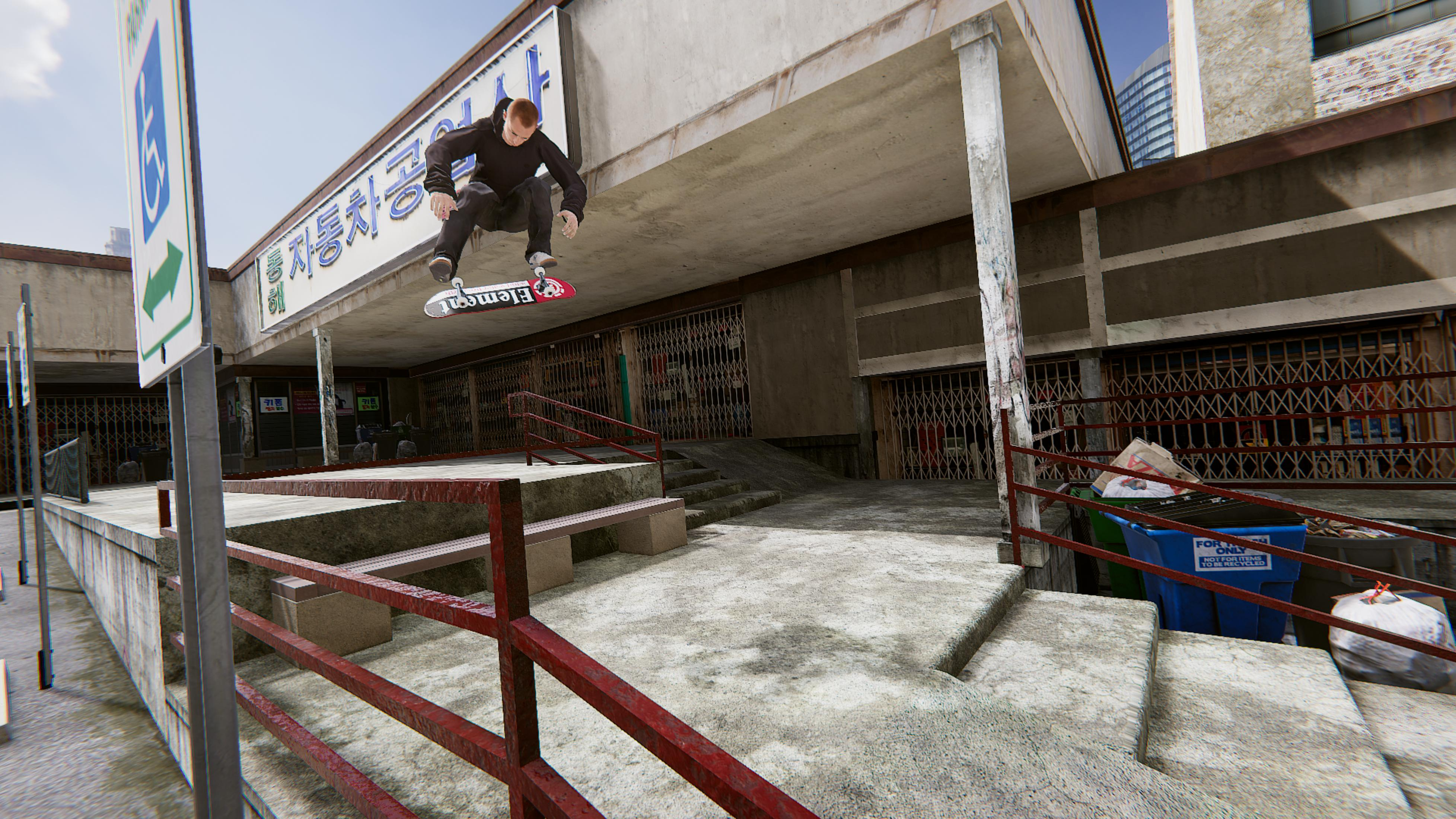 Skateboarder skacze z deskorolką Element przed budynkiem z roletami.
