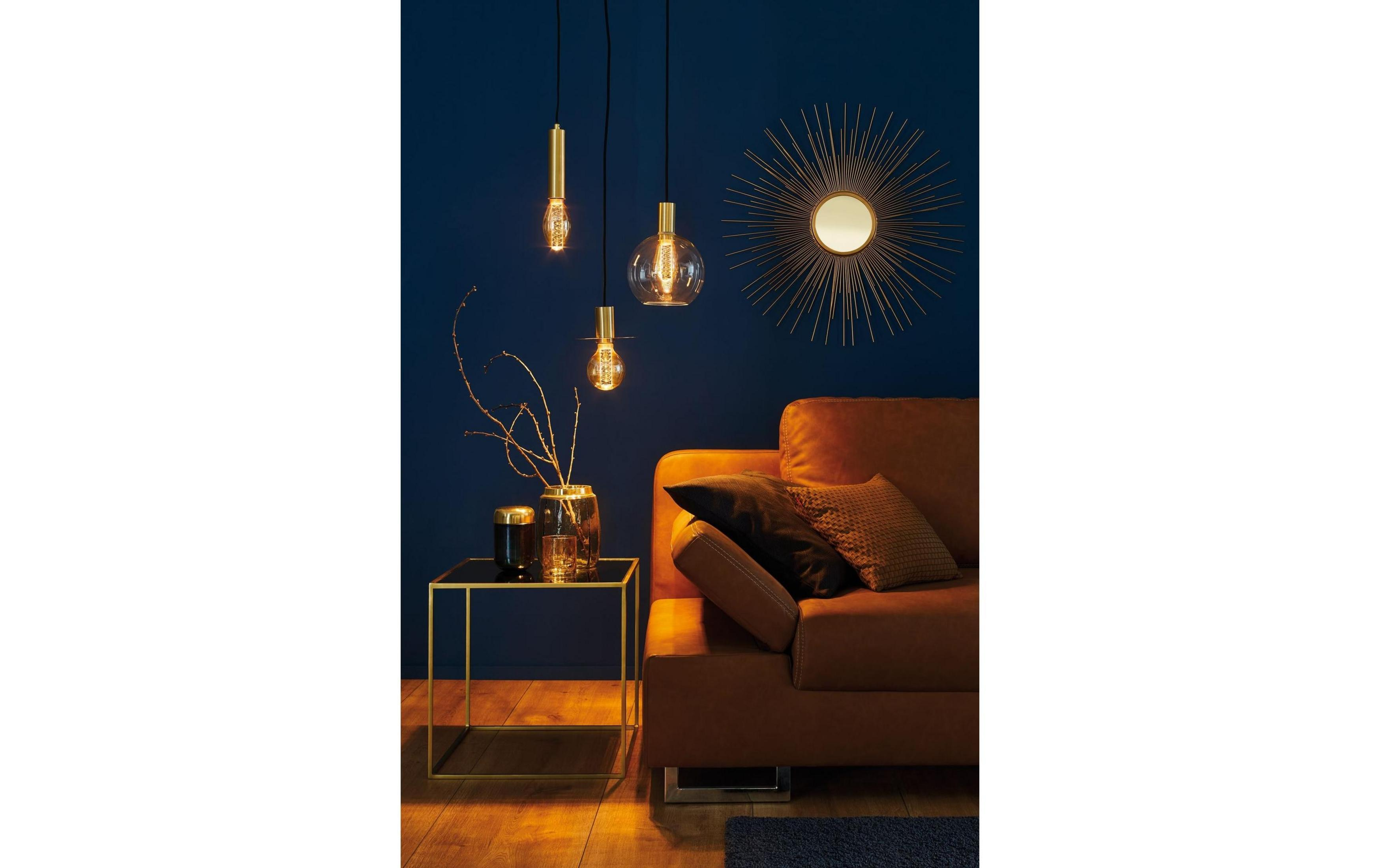 Brązowa sofa z poduszkami przed ciemnoniebieską ścianą z lampami i lustrem.